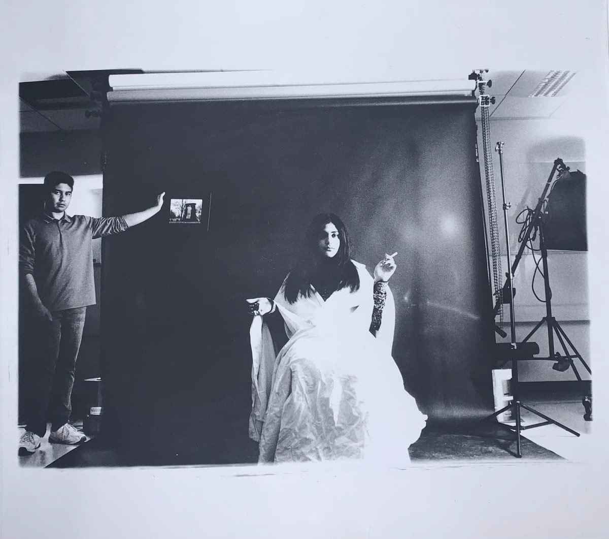 A black and white photo of a woman and man posing in front of a black backdrop