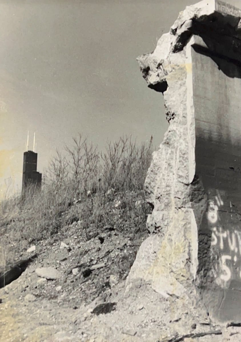 Black and white photograph of a wall from building ruins with the Willis Tower in the background