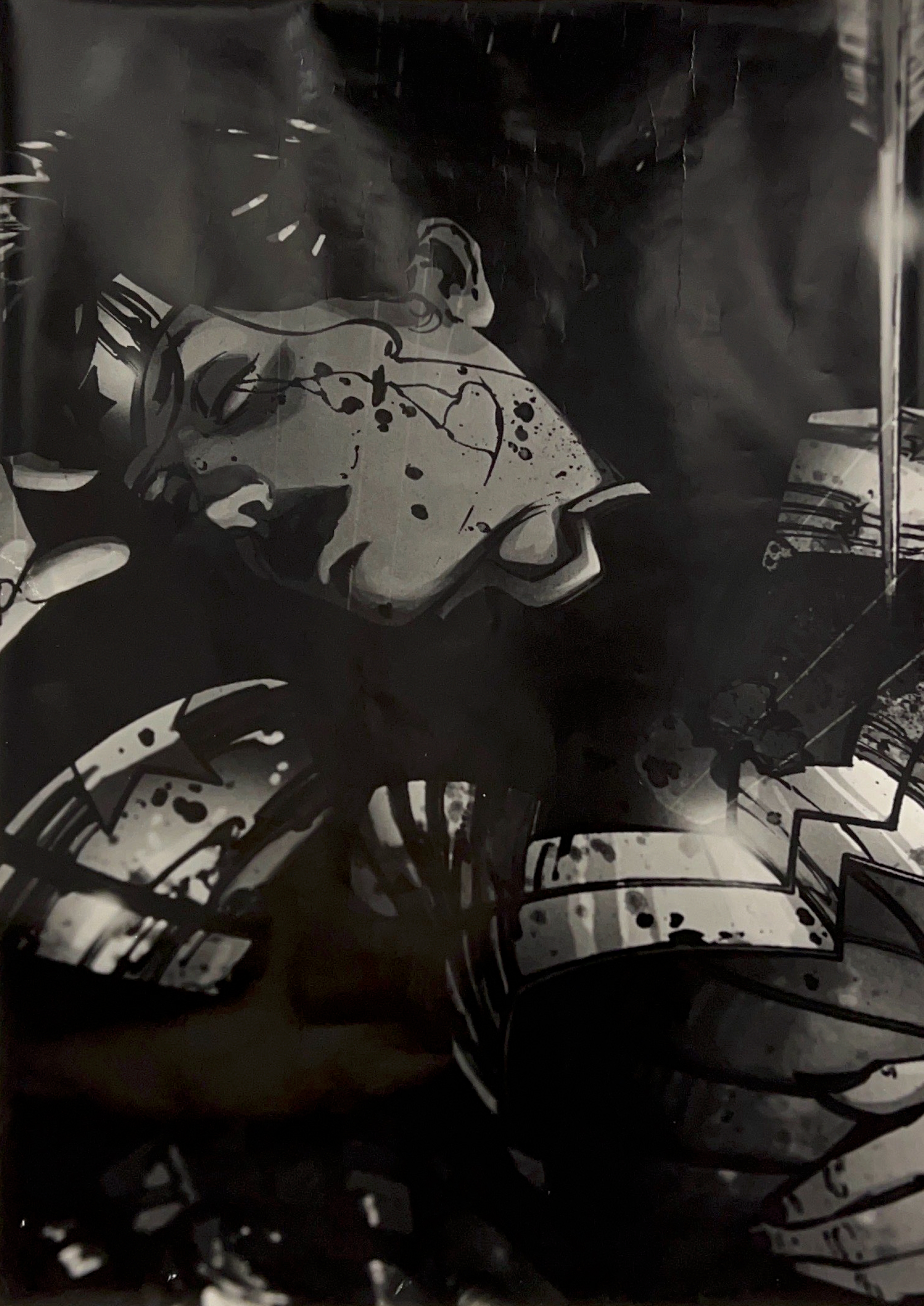 Black and white up-close photograph of a comic illustration of Wonder Woman who is unconscious with an arrow in her chest and blood spattered on her uniform and face.