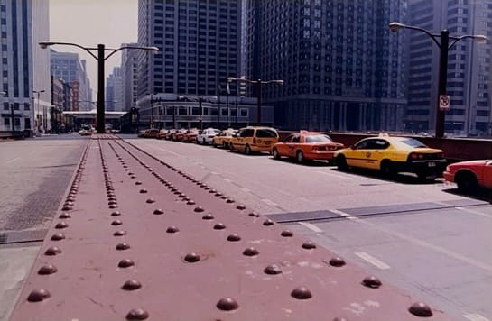 Color photograph of a road bridge over the river in Chicago with taxis lined up in the farthest right lane.
