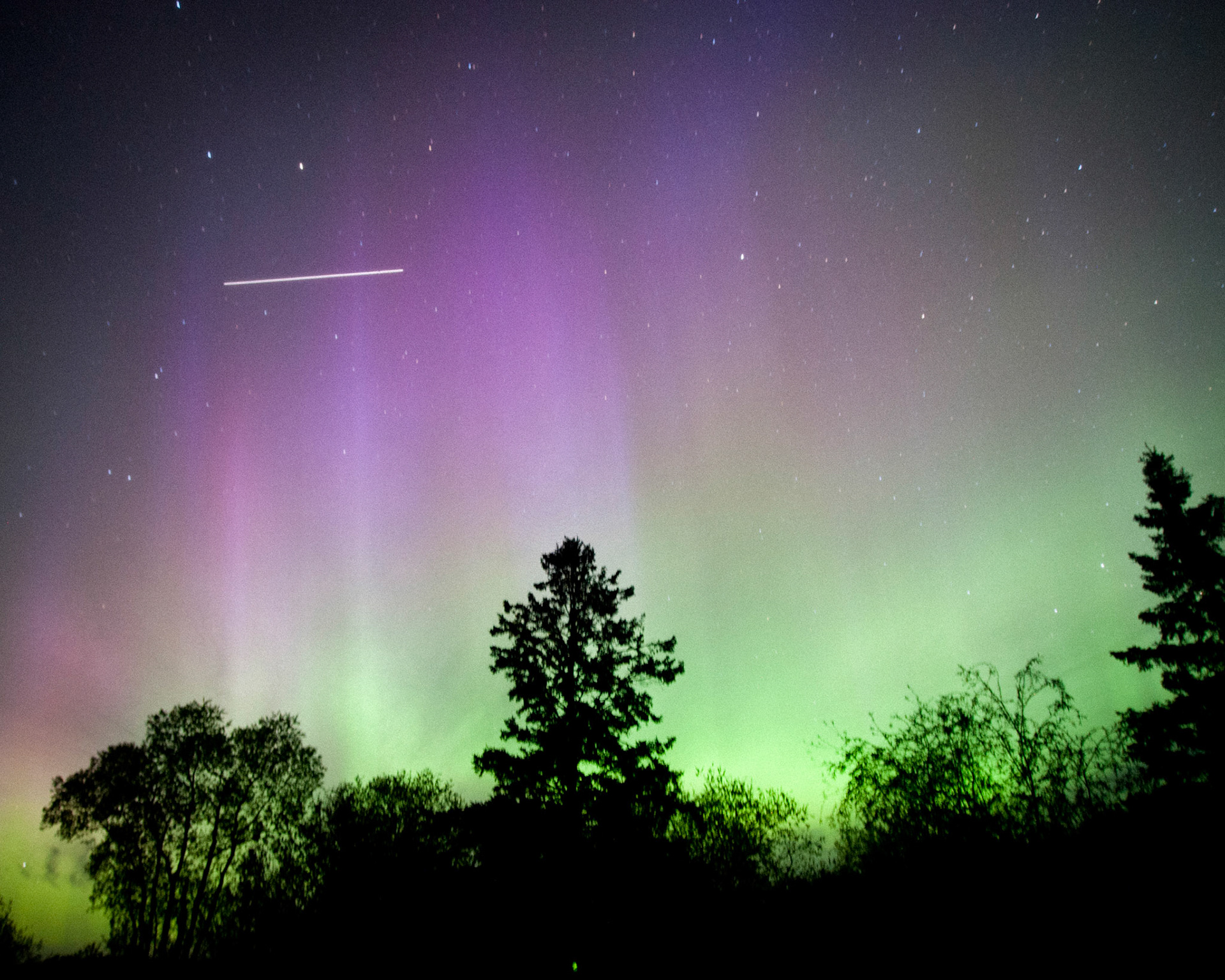 A 15 second time exposure shows the International Space Station passing above the Aurora Borealis (Northern Lights) as viewed From Blackduck Minnesota on the night of June 6th 2013. The Station; it's 250-260 mile high orbit flies well above the Aurora that is caused by the interaction of charged particles and the upper atmosphere at an altitude of 80 to 200 miles. Photo by Justin Dernier