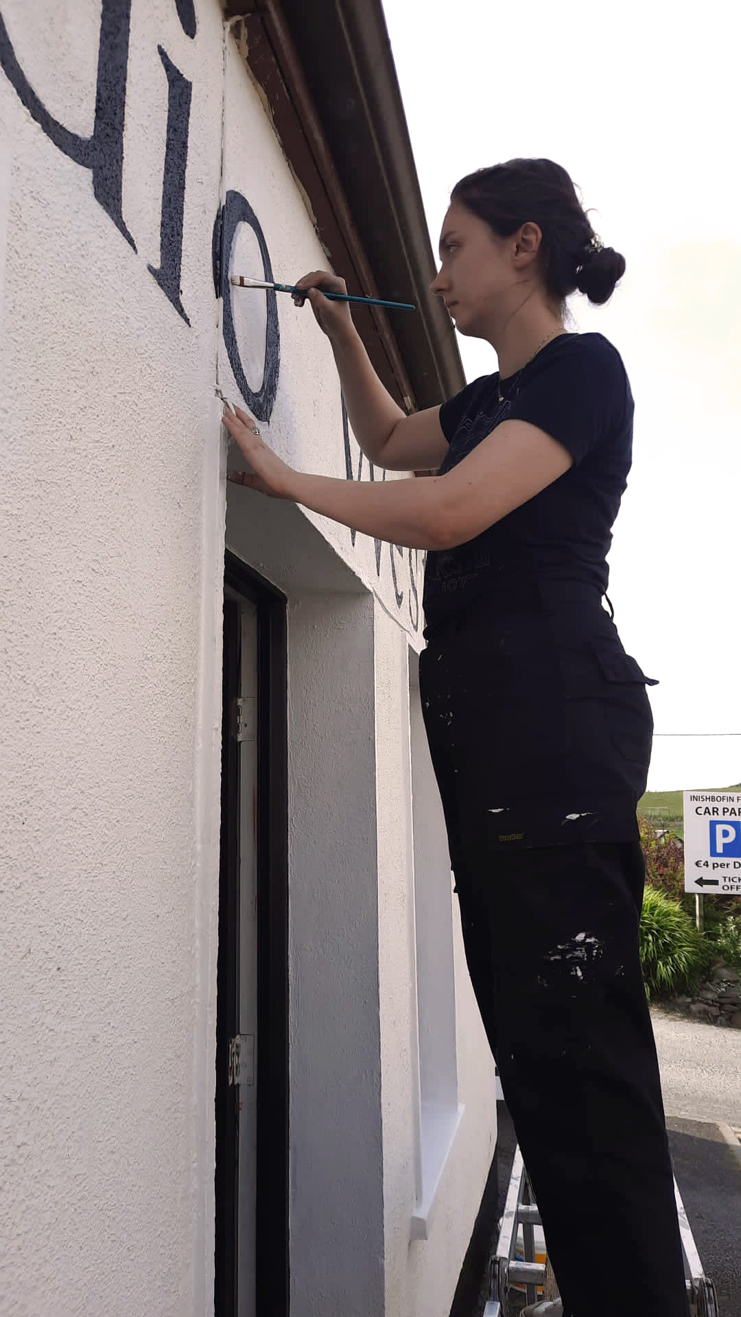 Painting our sign above the door- a look of serious concentration.