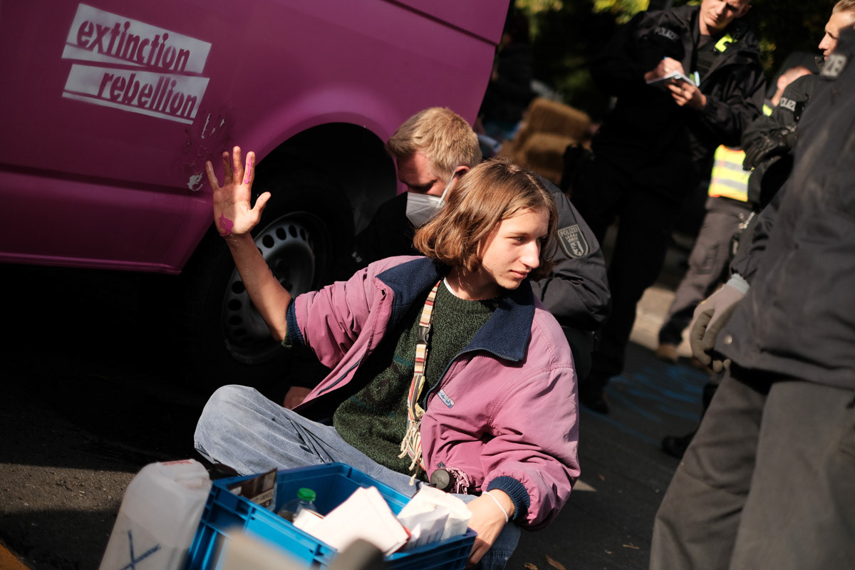 Police free the hand of an activist who had glued themselves to an immobilised vehicle.