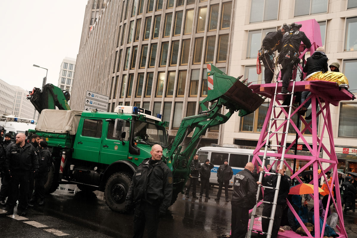 Police employ heavy machinery to dismantle an model oil rig used to block a Berlin intersection.