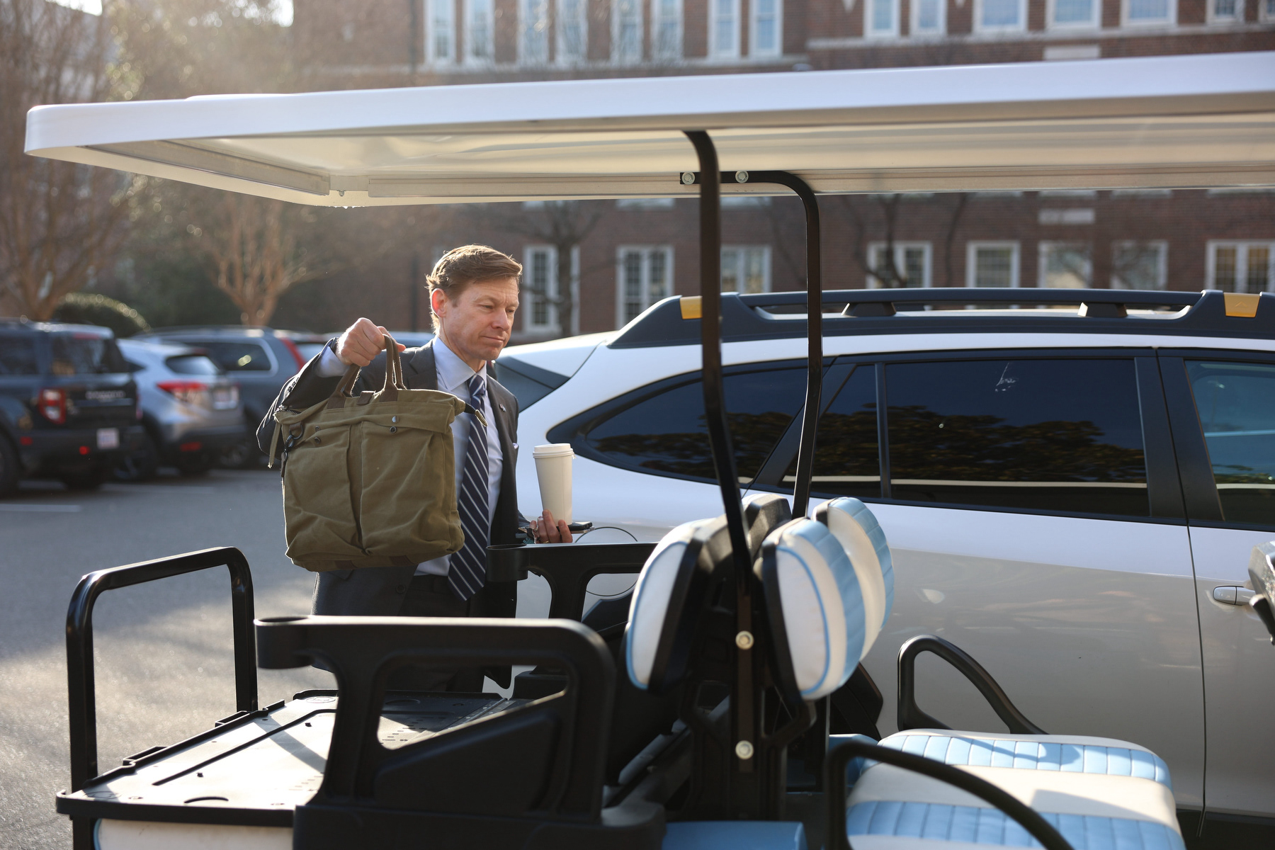 UNC Chancellor Lee Roberts grabs his bag out of a golf cart as he walks to South Building on Wednesday, March 4, 2026. Roberts was carrying two phones and a cup of green tea, and walked with Senior Director of UNC Media Relations Kevin Best back to South Building.