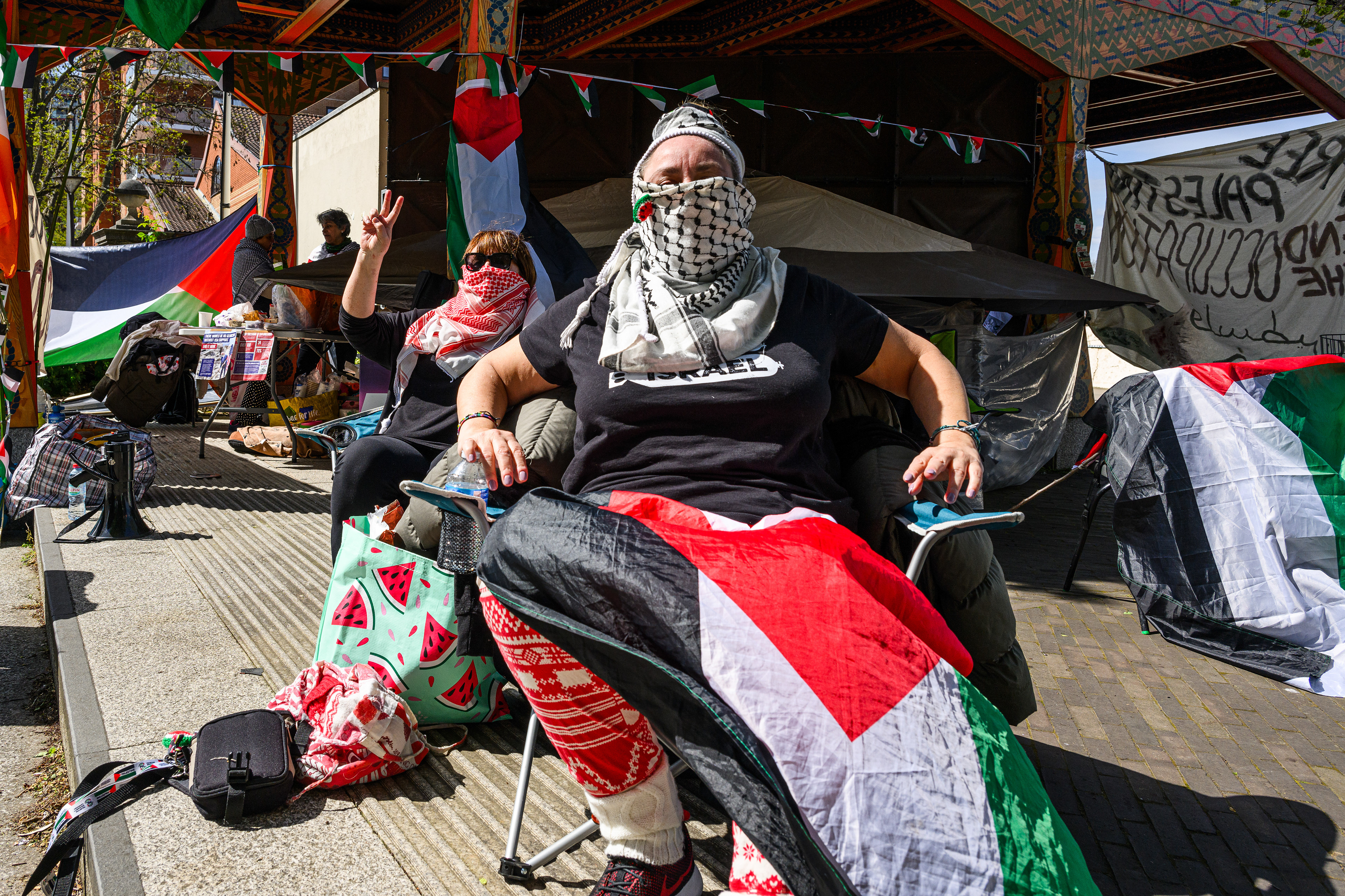 Two protesters know as "S" and "S" sit in camping chairs alongside the road in front of the protest camp. They sit and shout slogans hoping that the US Embassy will hear them.
