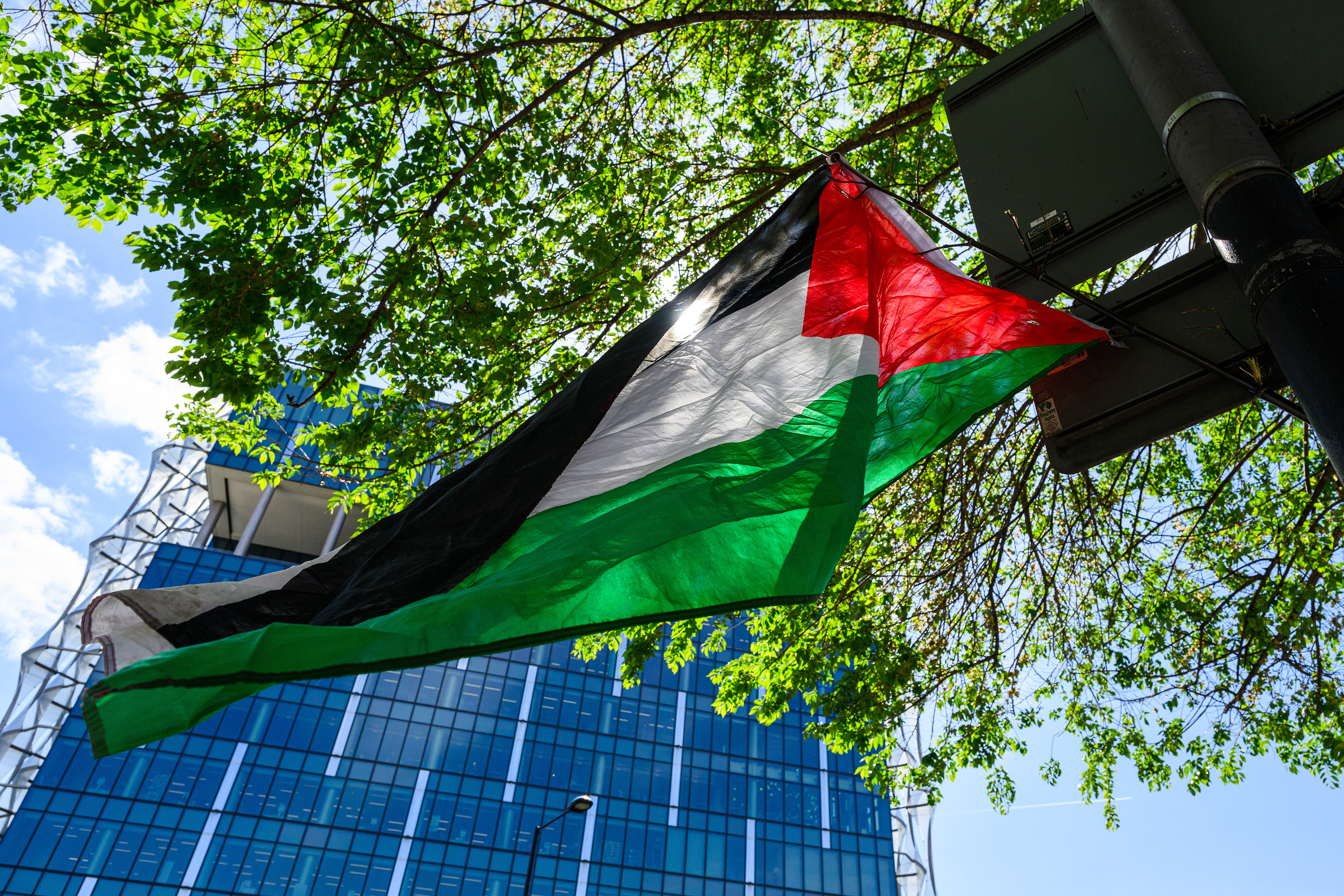 A Palestine flag hangs from a sign post. The US Embassy can be seen in the background.