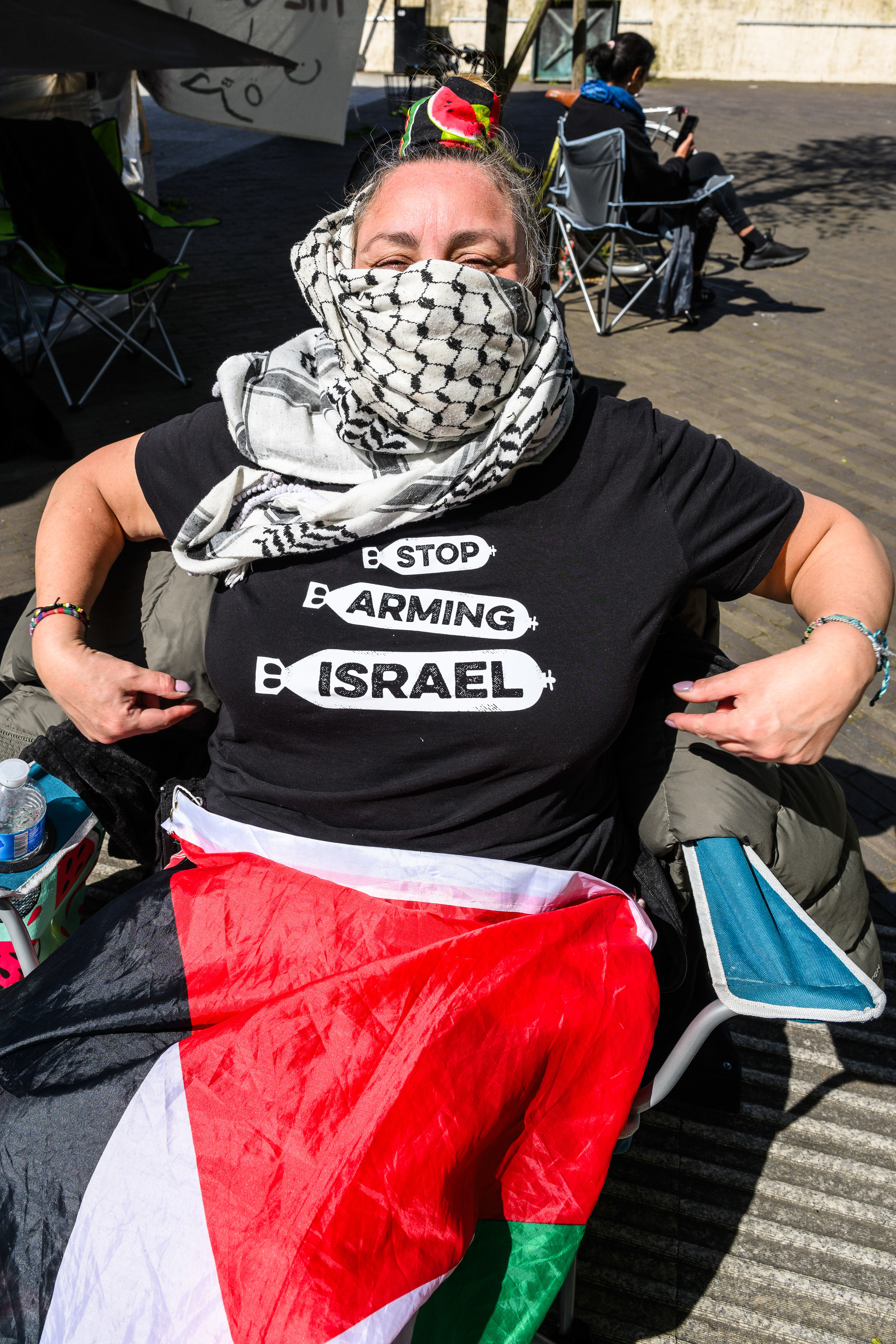 A protester known as "S" shows off her t-shirt whilst sitting in a camping chair outside the US Embassy.