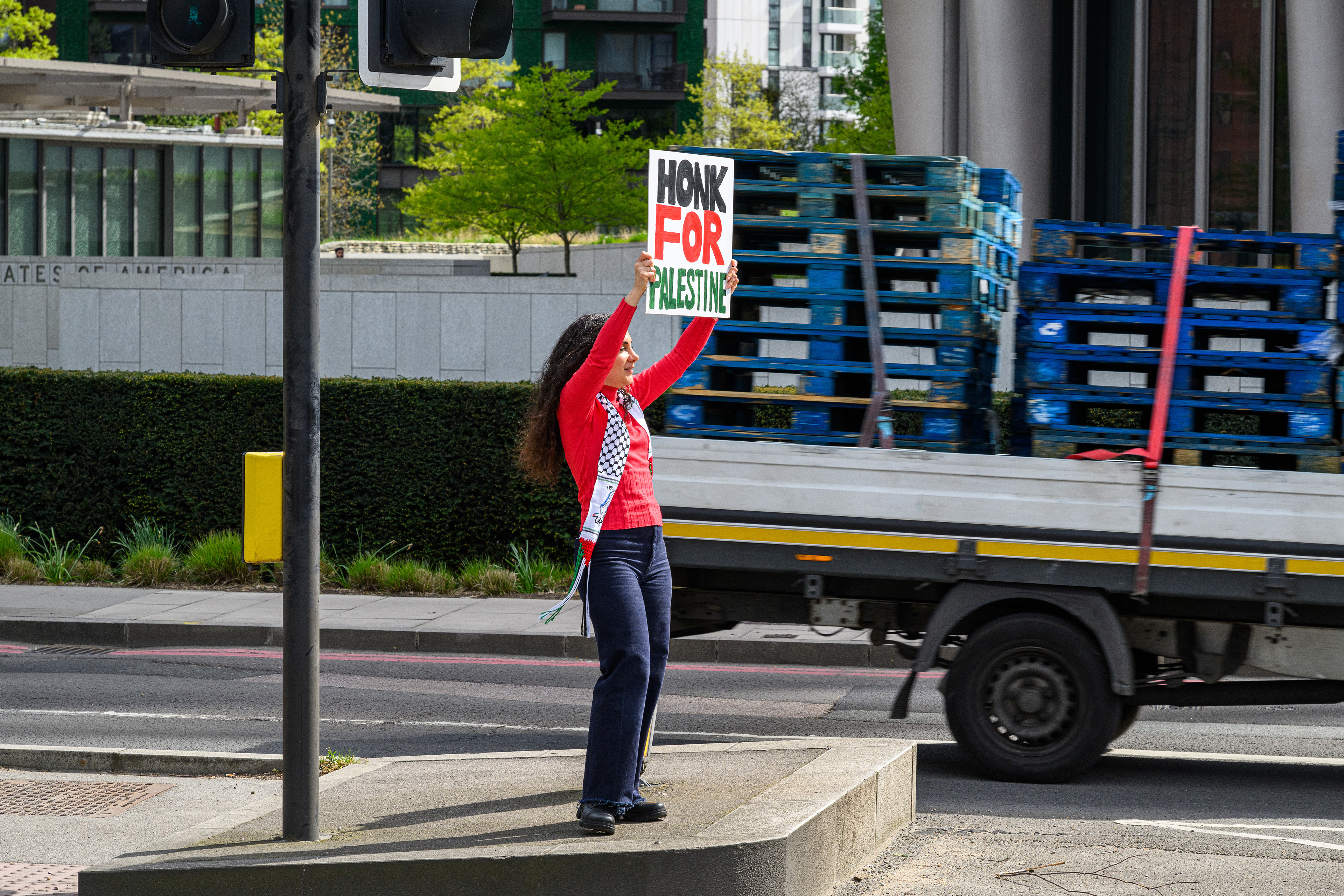 A roadside protester holds a placard asking drivers to honk for Palestine