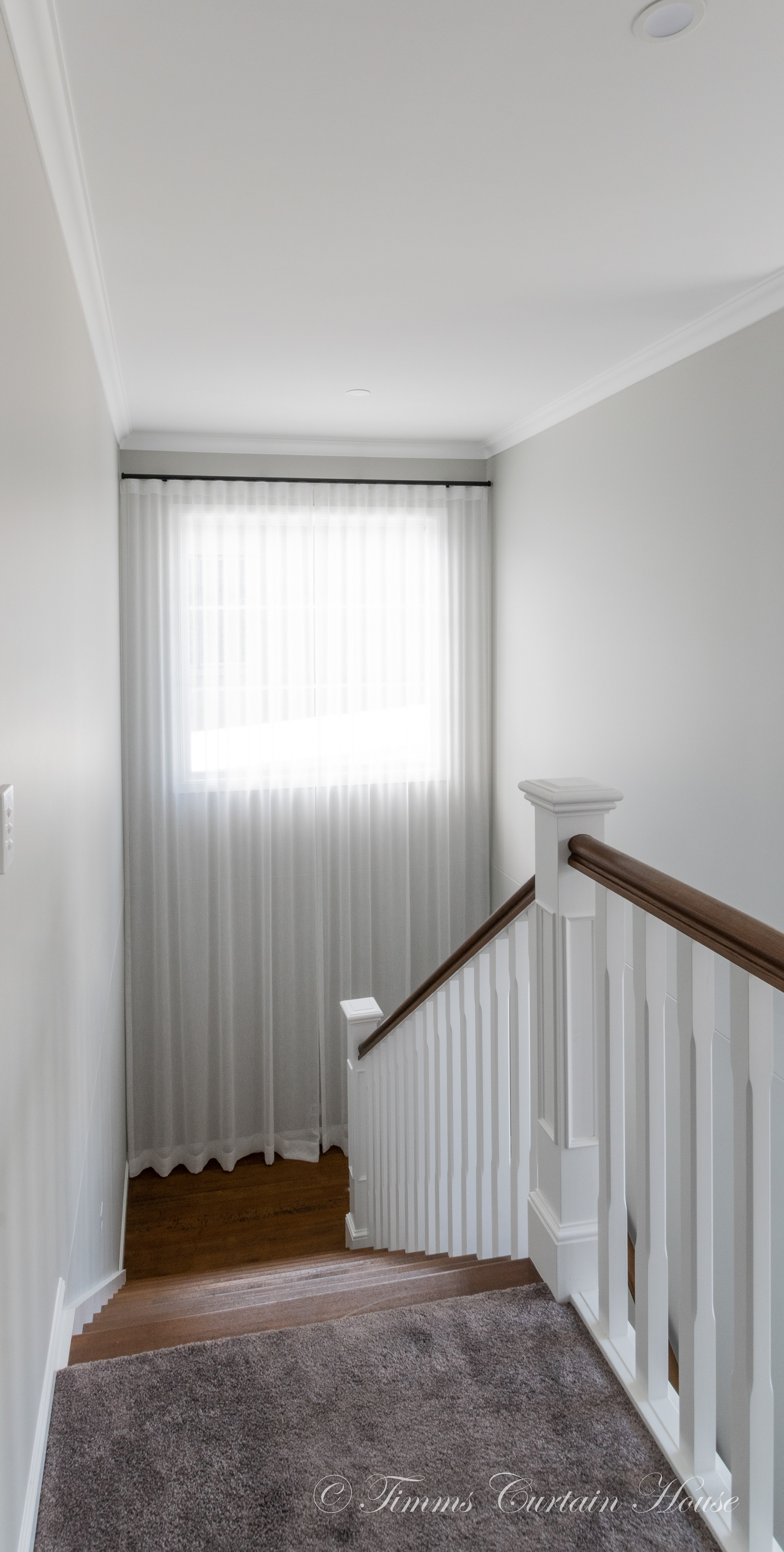 Stairwell with white sheers, black pole, wall mount