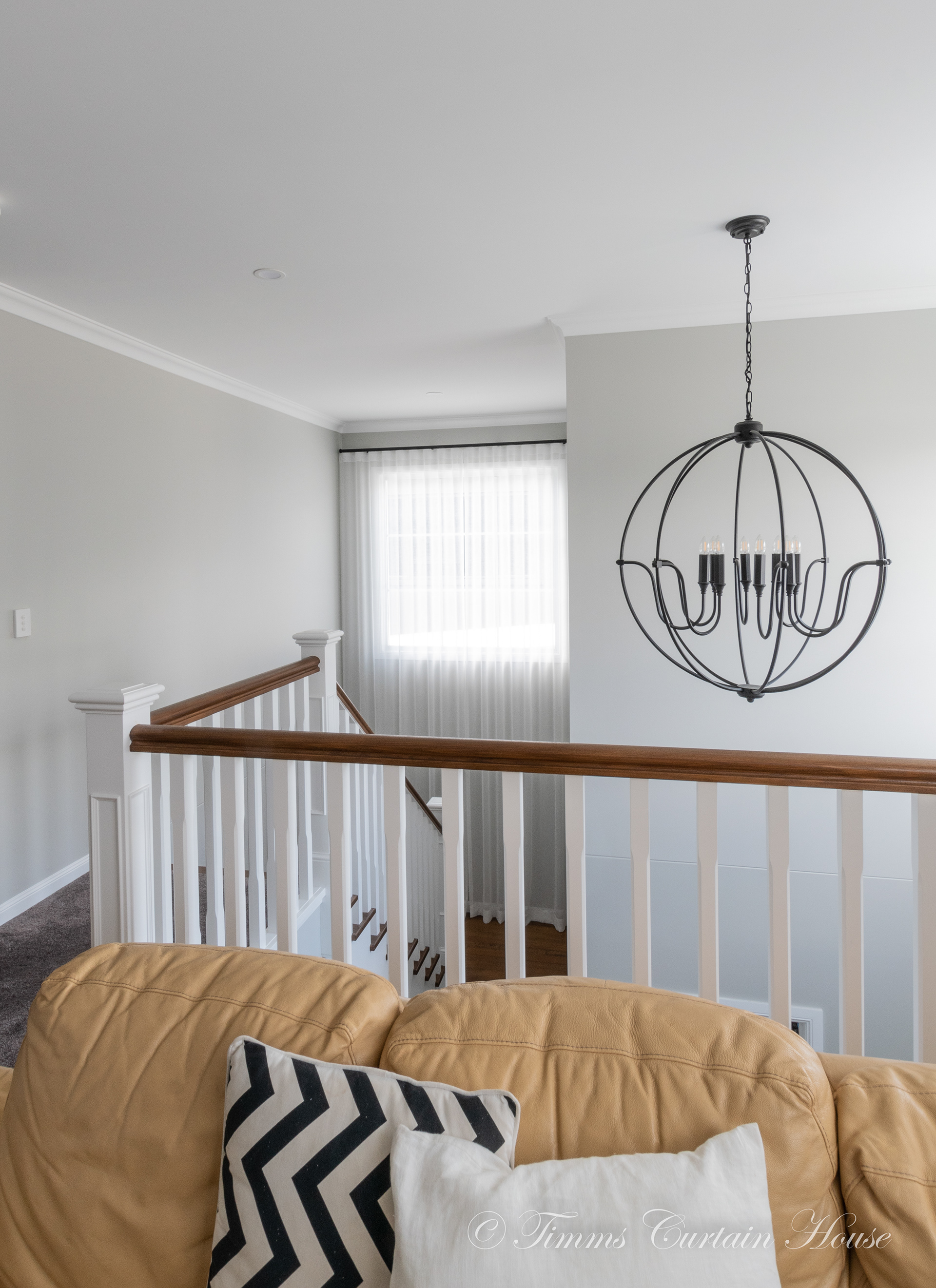 Stairwell with white sheers, black pole, wall mount