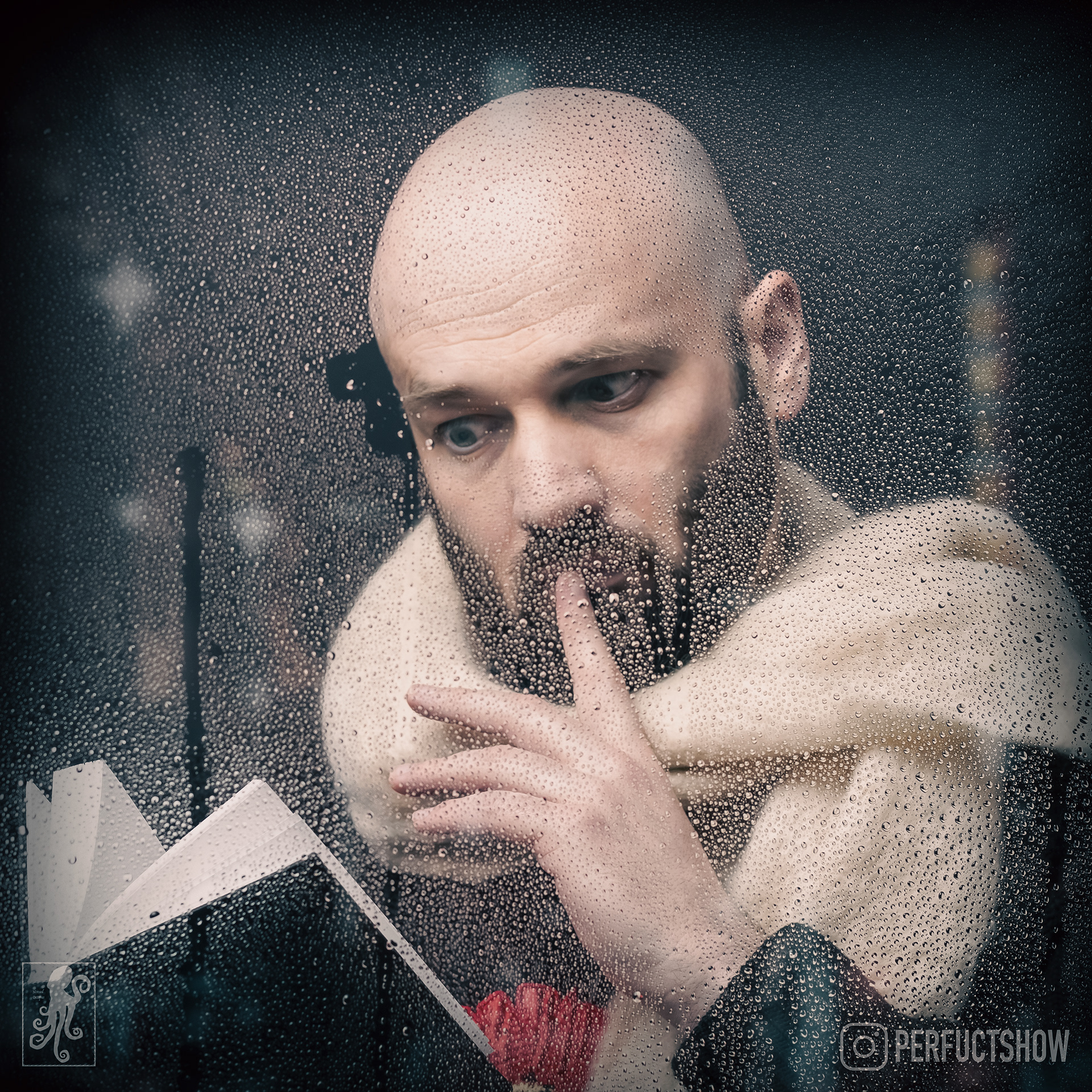 Comedian Dan Bain wears a wooly scarf and can be seen through a rainy window checking his diary to see if he is available for corporate performances on a specific date.