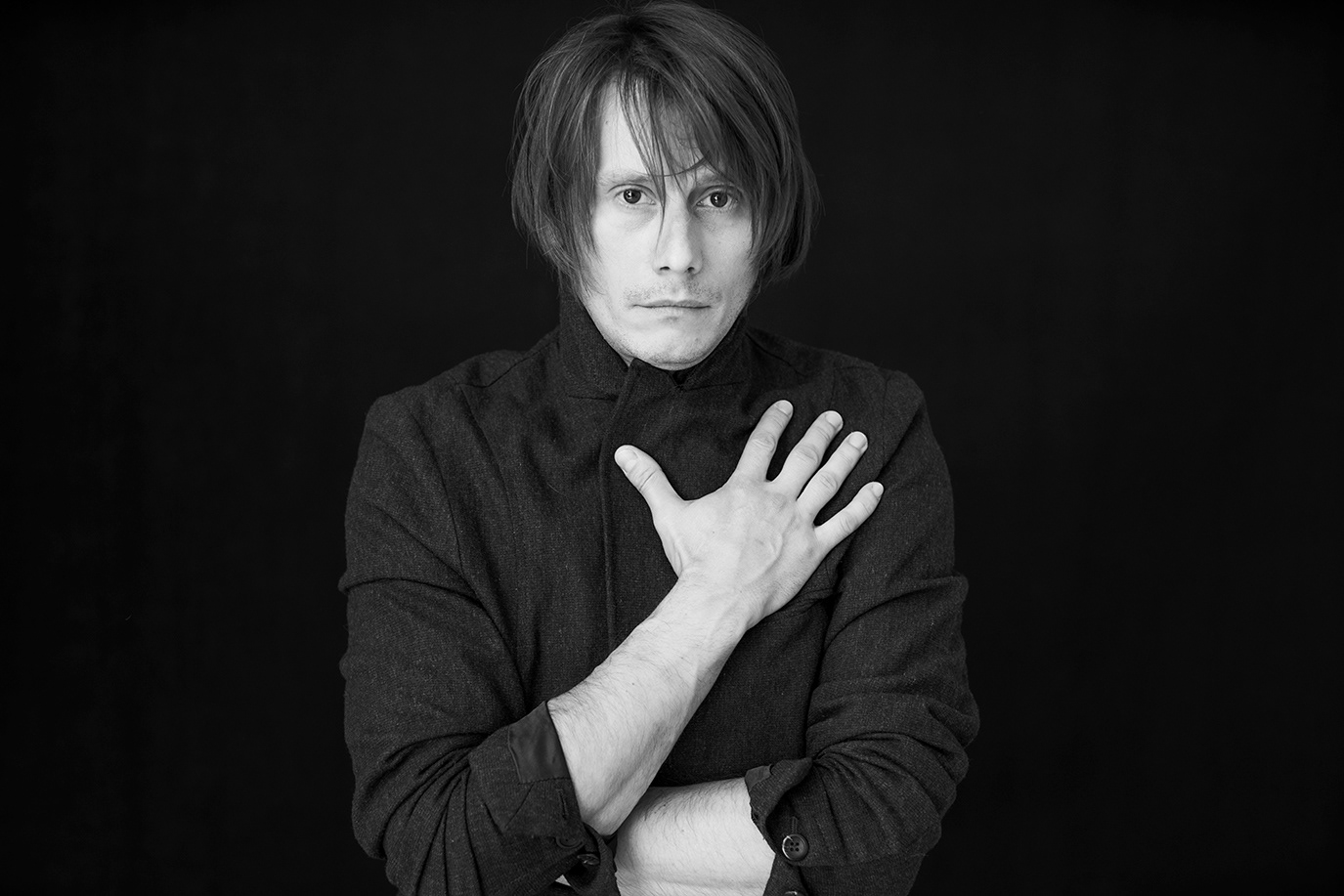 Marius Manole holding one hand to his chest in a black-and-white portrait, photographed by Alex Gâlmeanu.