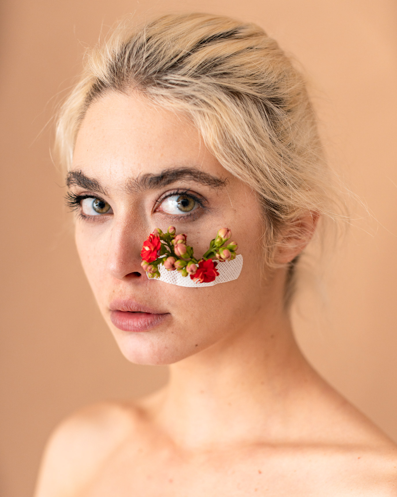 Close portrait of model Georgiana Saraev with small flowers fixed beneath one eye, photographed by Alex Gâlmeanu.