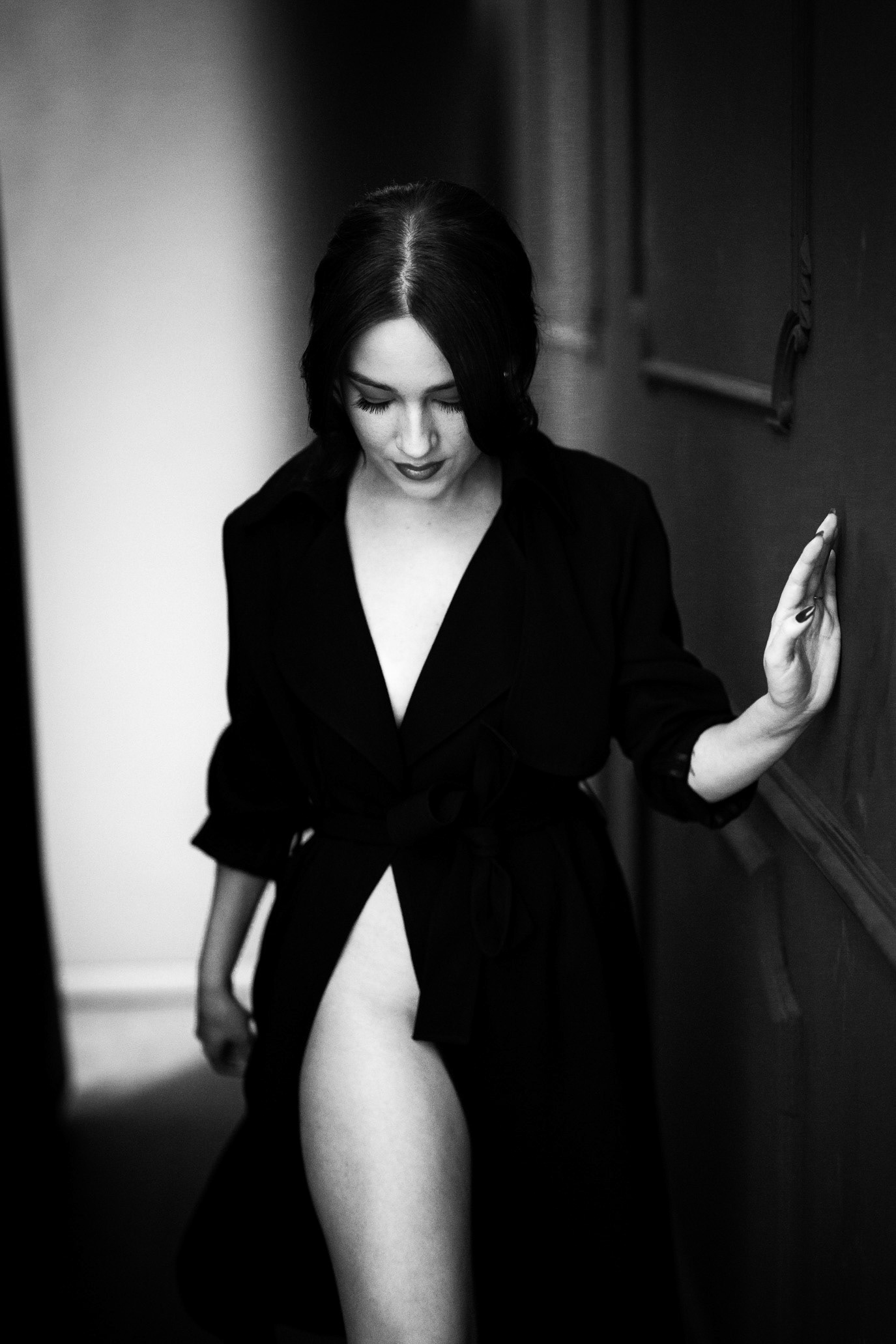 Black-and-white portrait of content creator Mihaela Pantea in a dark robe, looking down in doorway light, photographed by Alex Gâlmeanu.