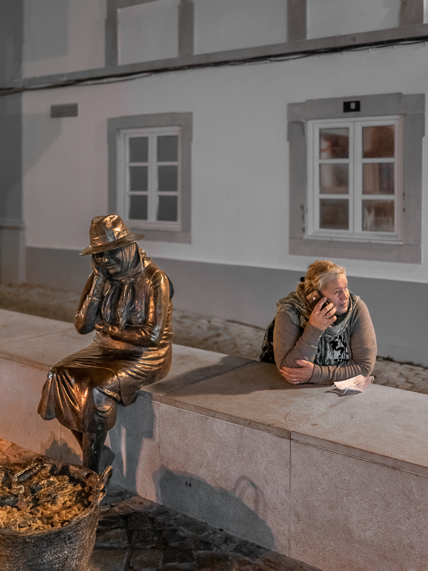 A woman mirroring the pose of a bronze seated figure in Loulé, Portugal. Photograph by Alex Galmeanu.
