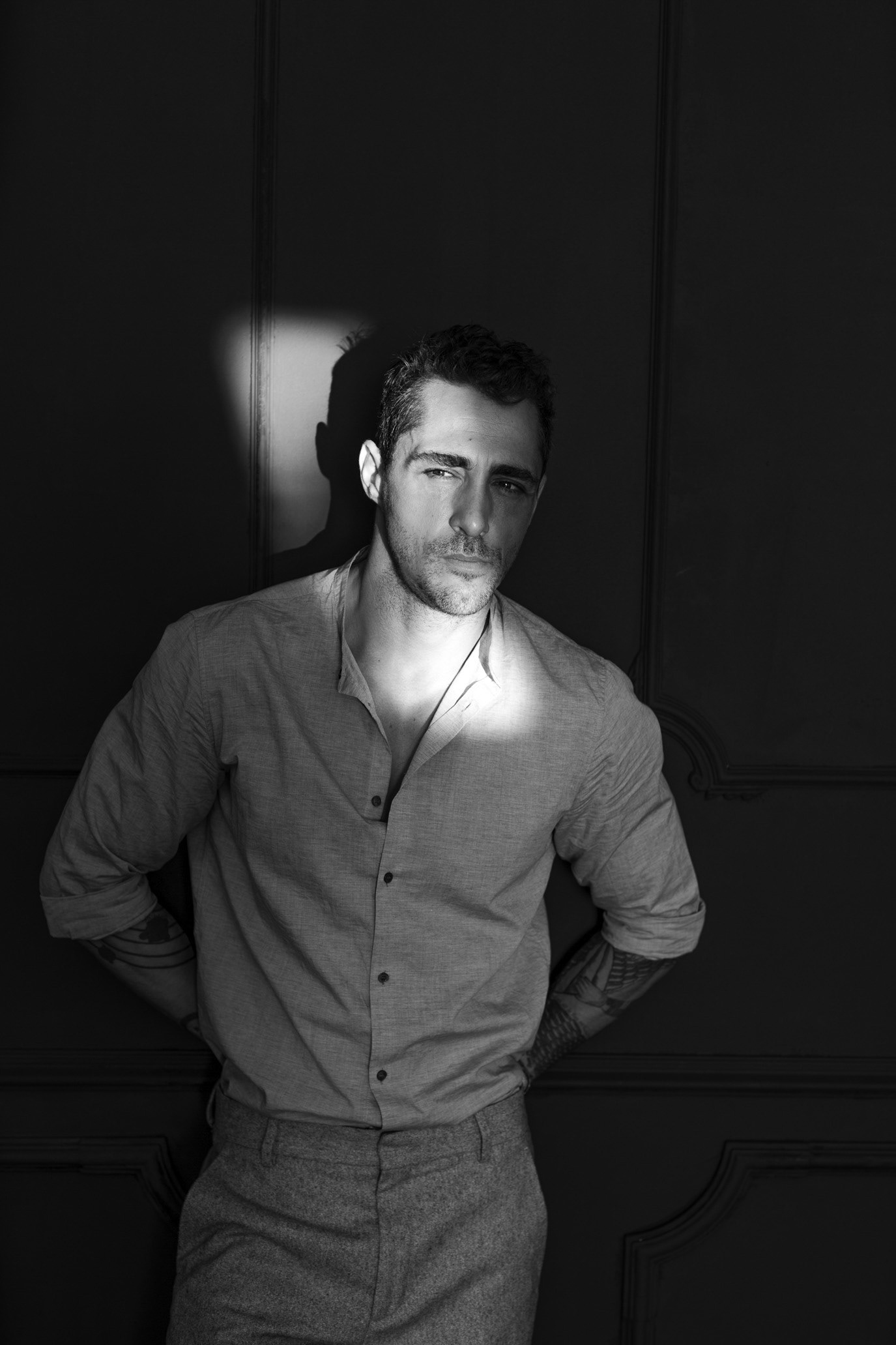 Black-and-white full-length portrait of actor Vladimir Draghia standing against a dark studio background, photographed by Alex Gâlmeanu.