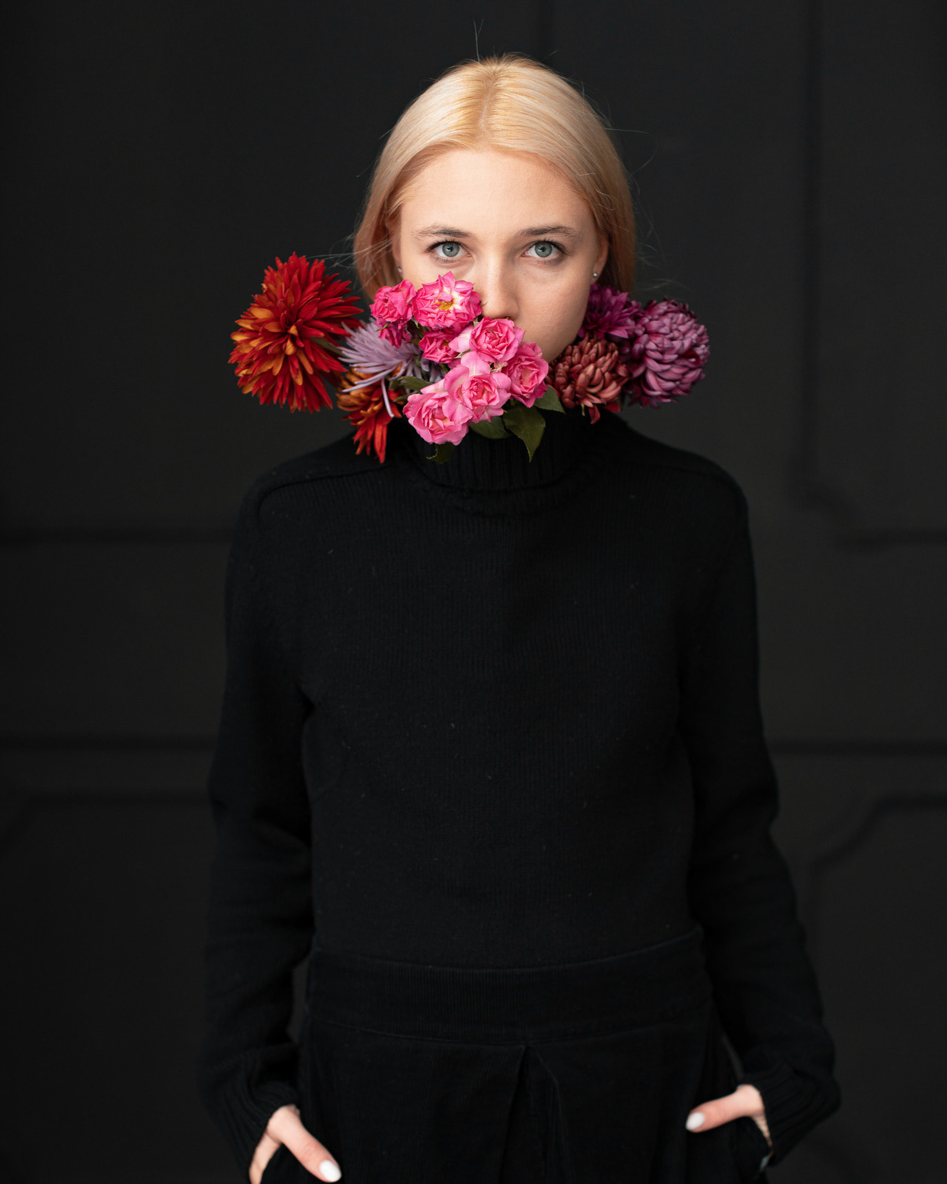 Portrait of model Elena Maria Popescu with colorful flowers covering her mouth, photographed by Alex Gâlmeanu.