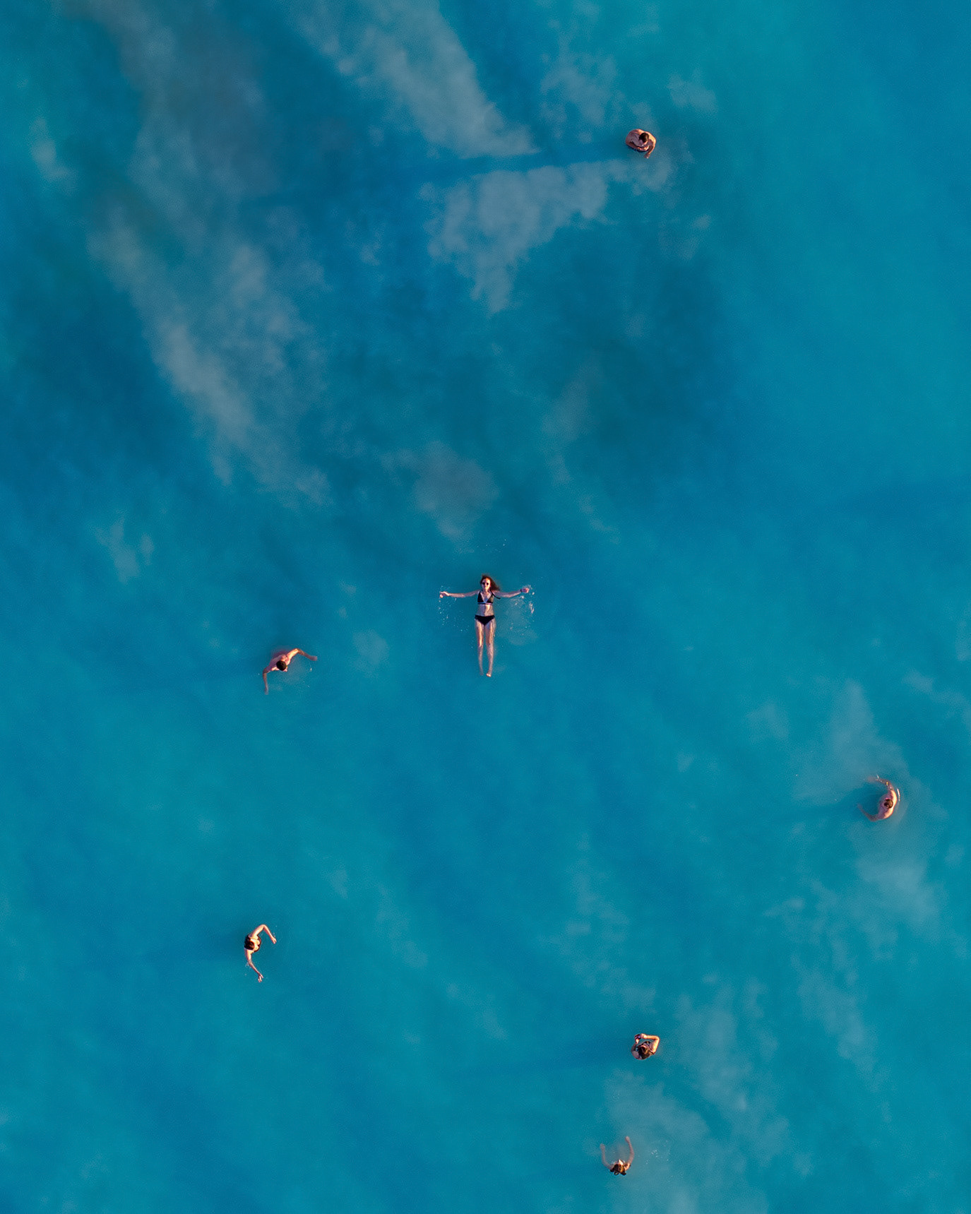 Swimmers dispersed through turquoise water seen from above in Rosignano Marittimo, Italy. Photograph by Alex Galmeanu.
