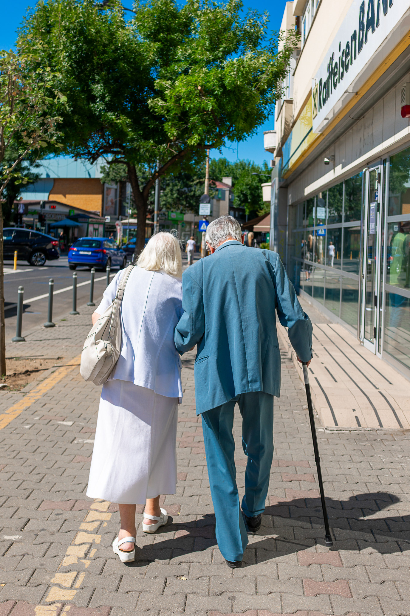 An elderly couple walking together, one using a cane, in Bucharest, Romania. Photograph by Alex Galmeanu.