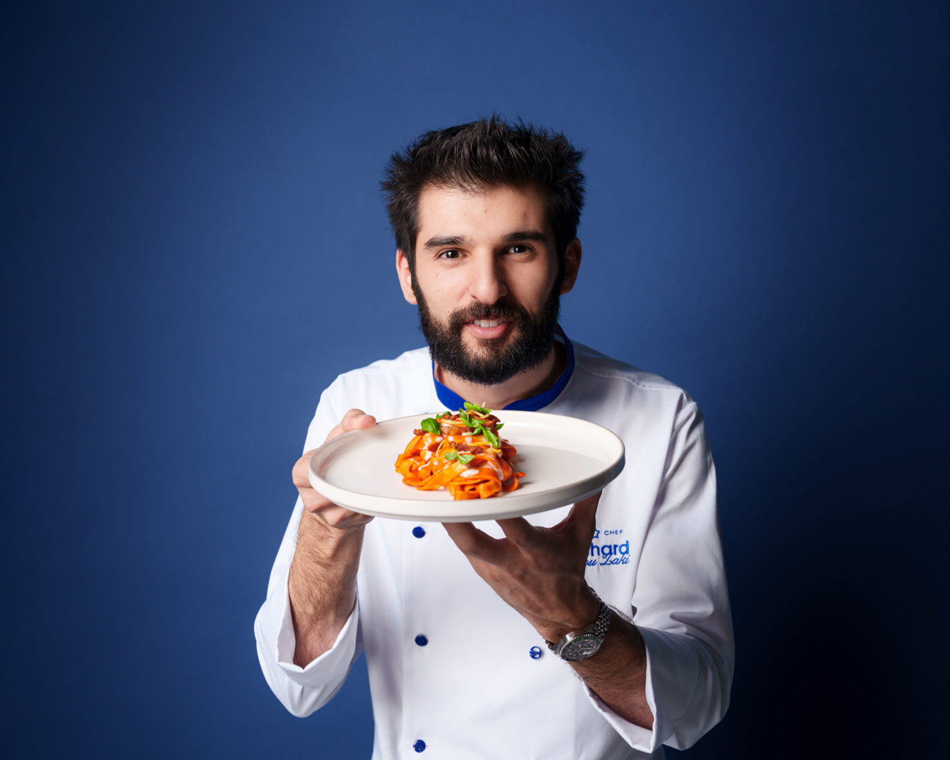 Chef Richard presenting a plate of pasta against a blue background for Peroni, photographed by Alex Gâlmeanu.