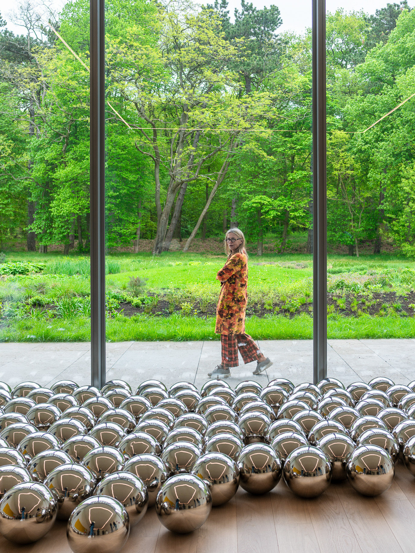 A woman seen beyond glass and rows of mirrored spheres in Wassenaar, Netherlands. Photograph by Alex Galmeanu.