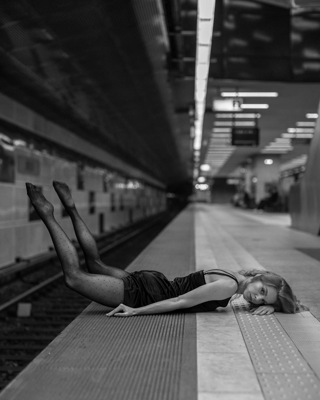 Anca Surdu lying on a railway platform with her legs raised, photographed by Alex Gâlmeanu.