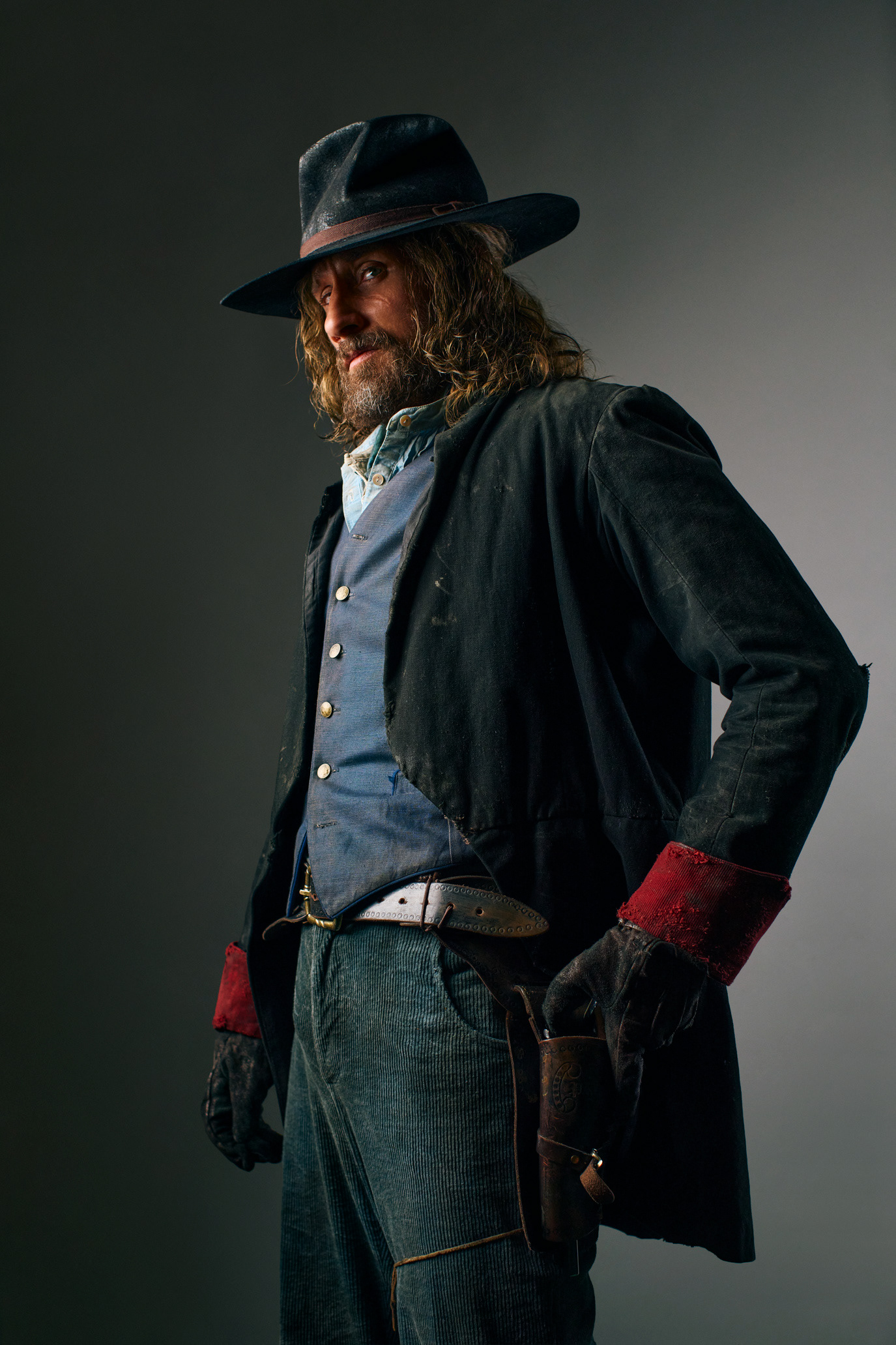 Matthias Schoenaerts standing in a dark western costume and hat, photographed by Alex Gâlmeanu.