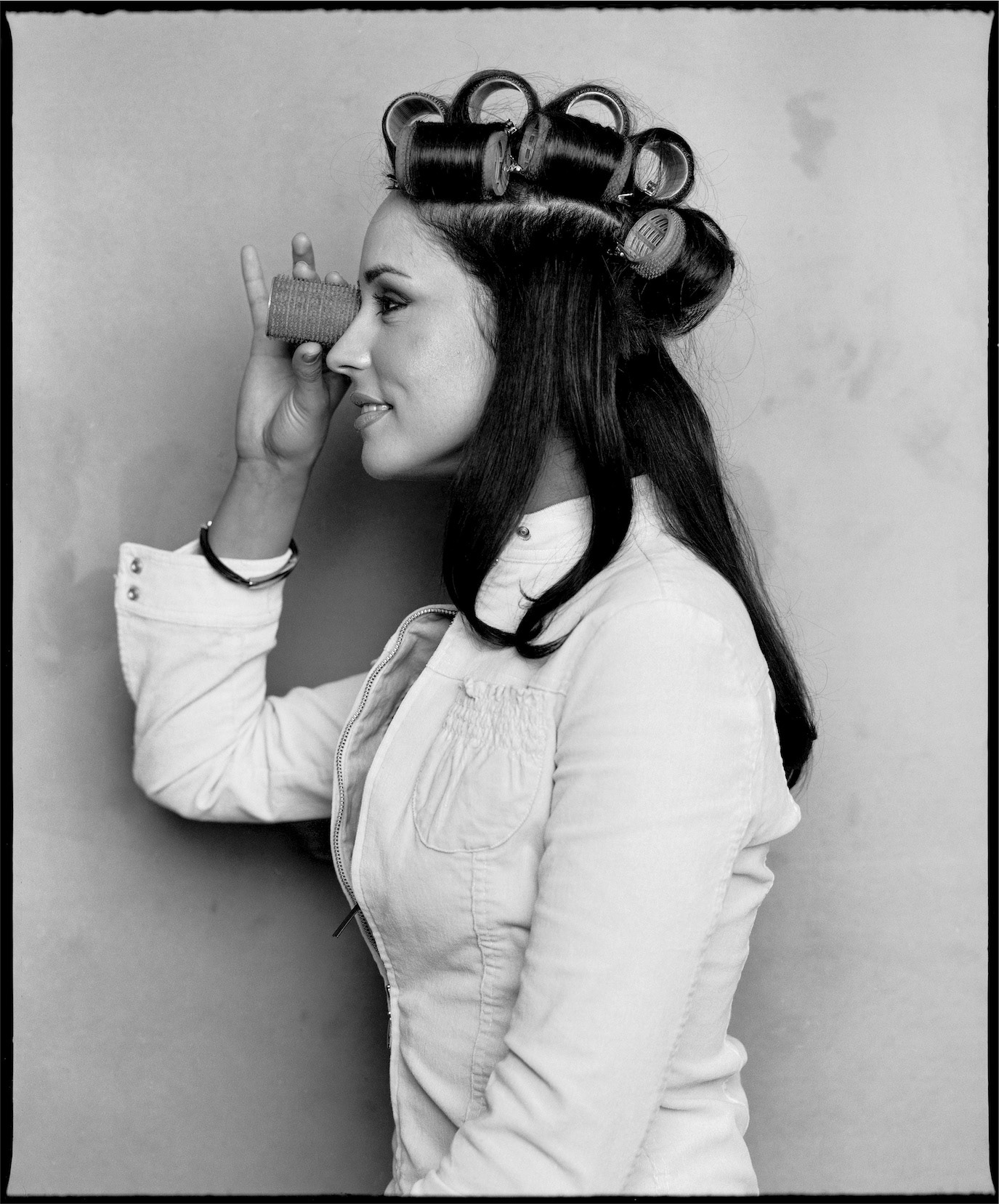 Andreea Marin wearing hair rollers and holding a small comb to one eye, photographed by Alex Gâlmeanu.