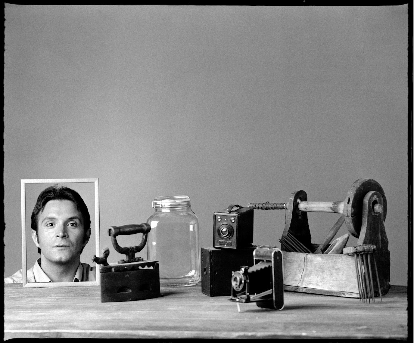 Daniel Buzdugan represented by a framed portrait among vintage cameras and tools, photographed by Alex Gâlmeanu.