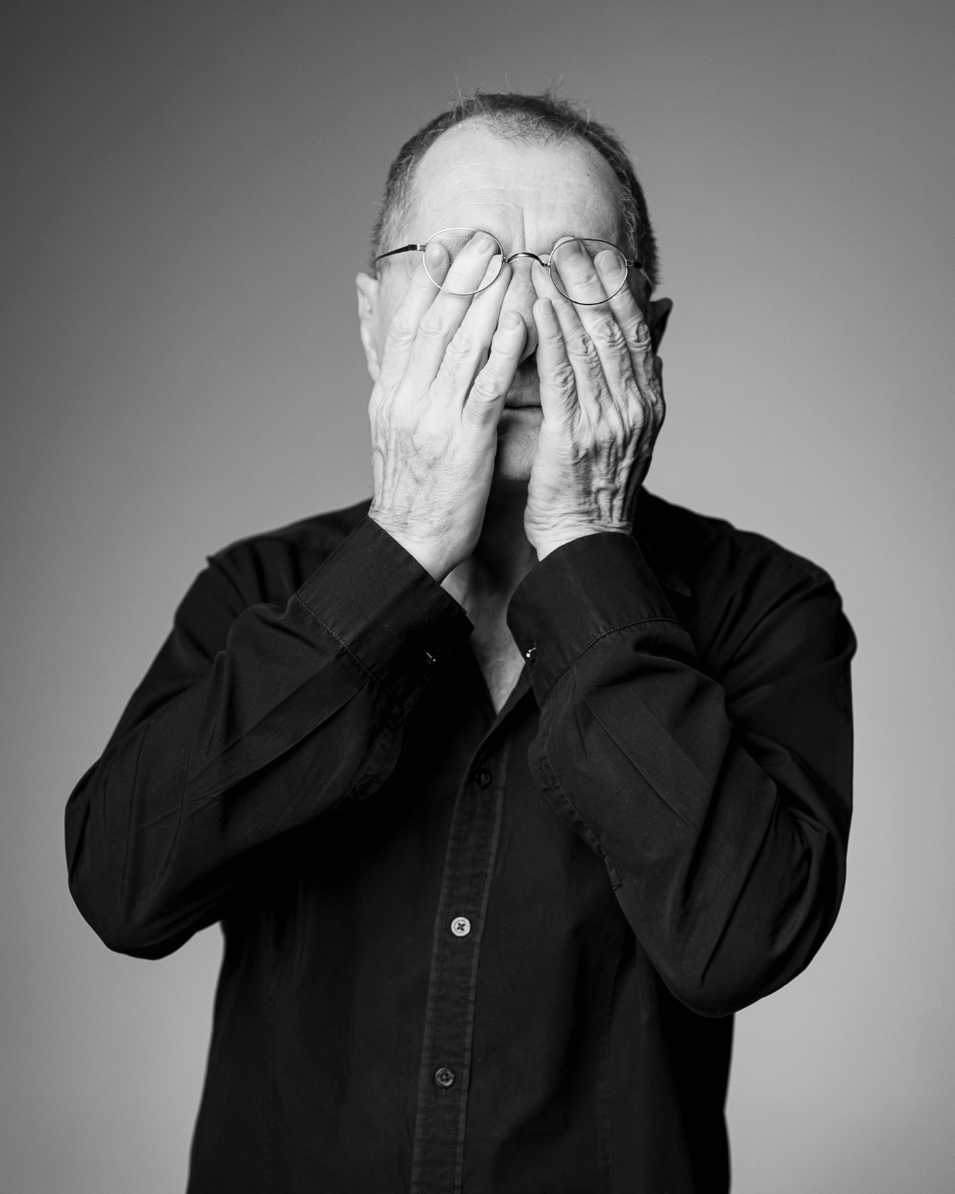 Horațiu Mălăele covering his face with both hands in a black-and-white portrait, photographed by Alex Gâlmeanu.