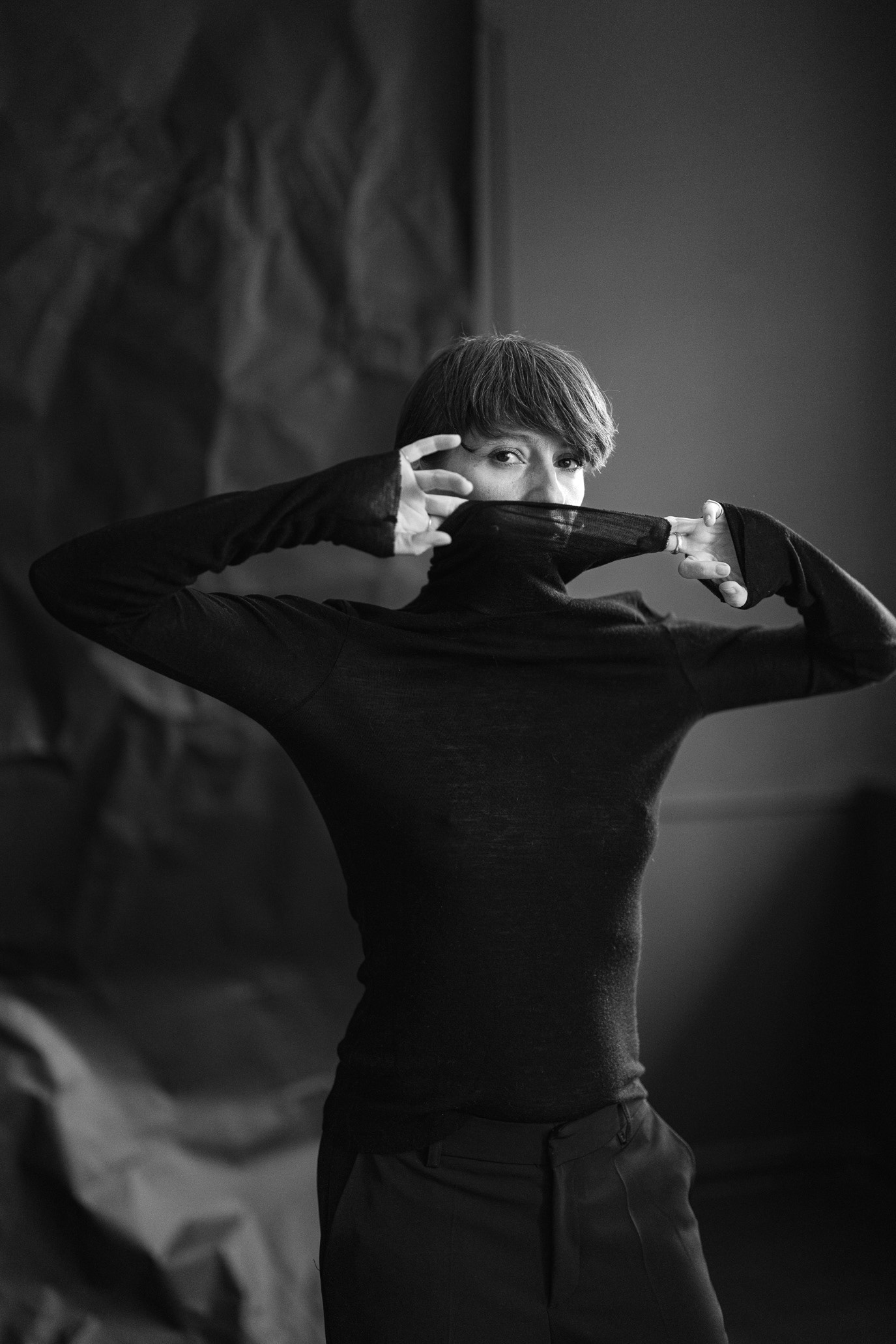 Black-and-white portrait of actor and dancer Judith State partially hiding her face in a raised black collar, photographed by Alex Gâlmeanu.