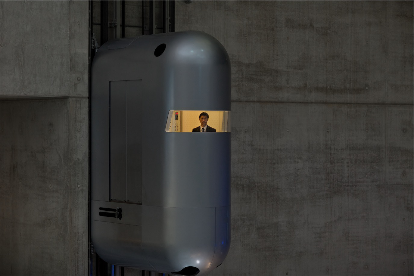 Ciprian Marica seen through the narrow window of a large metallic structure, photographed by Alex Gâlmeanu.