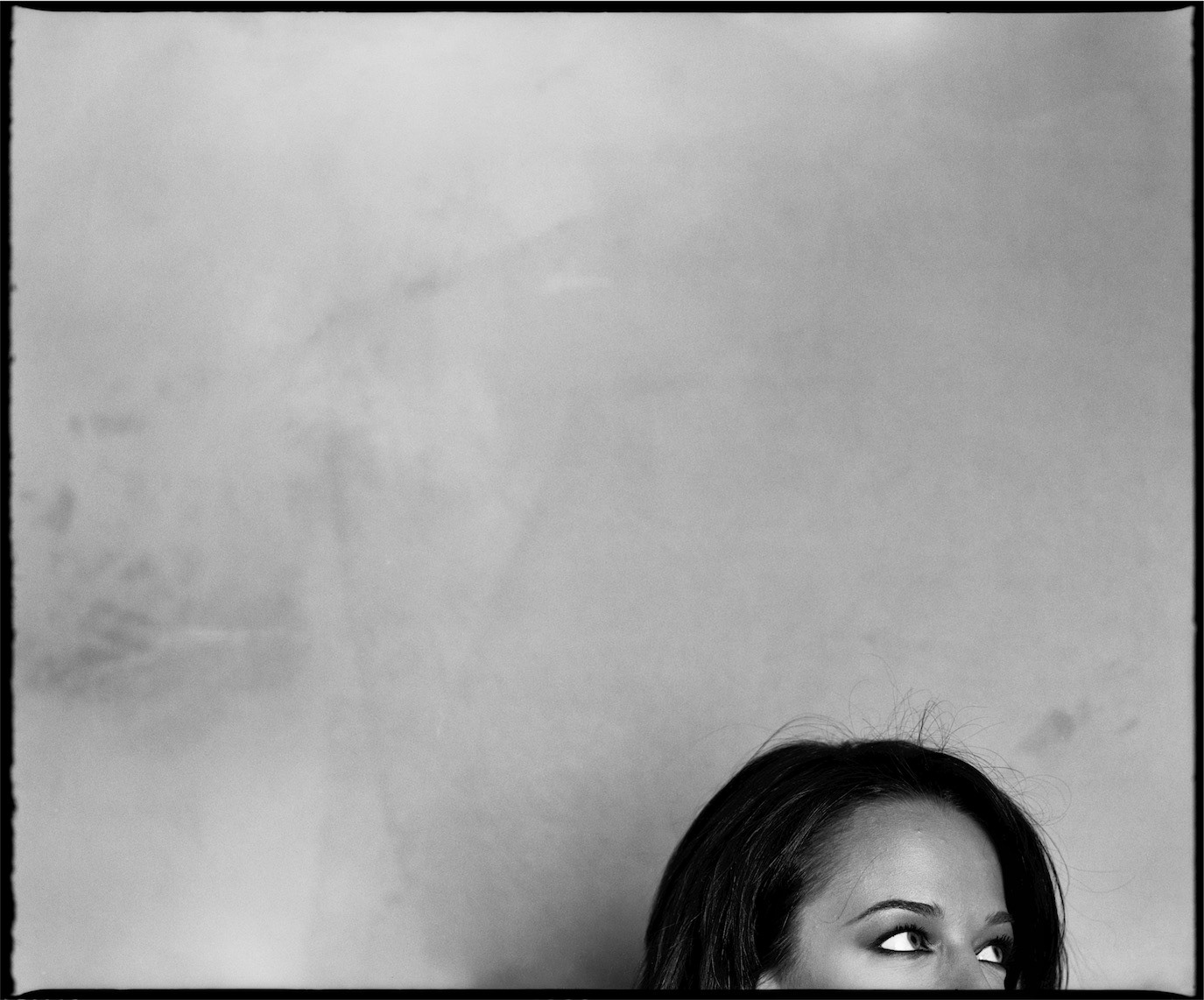 Andreea Raicu peeking into a black-and-white frame with only her eyes visible, photographed by Alex Gâlmeanu.