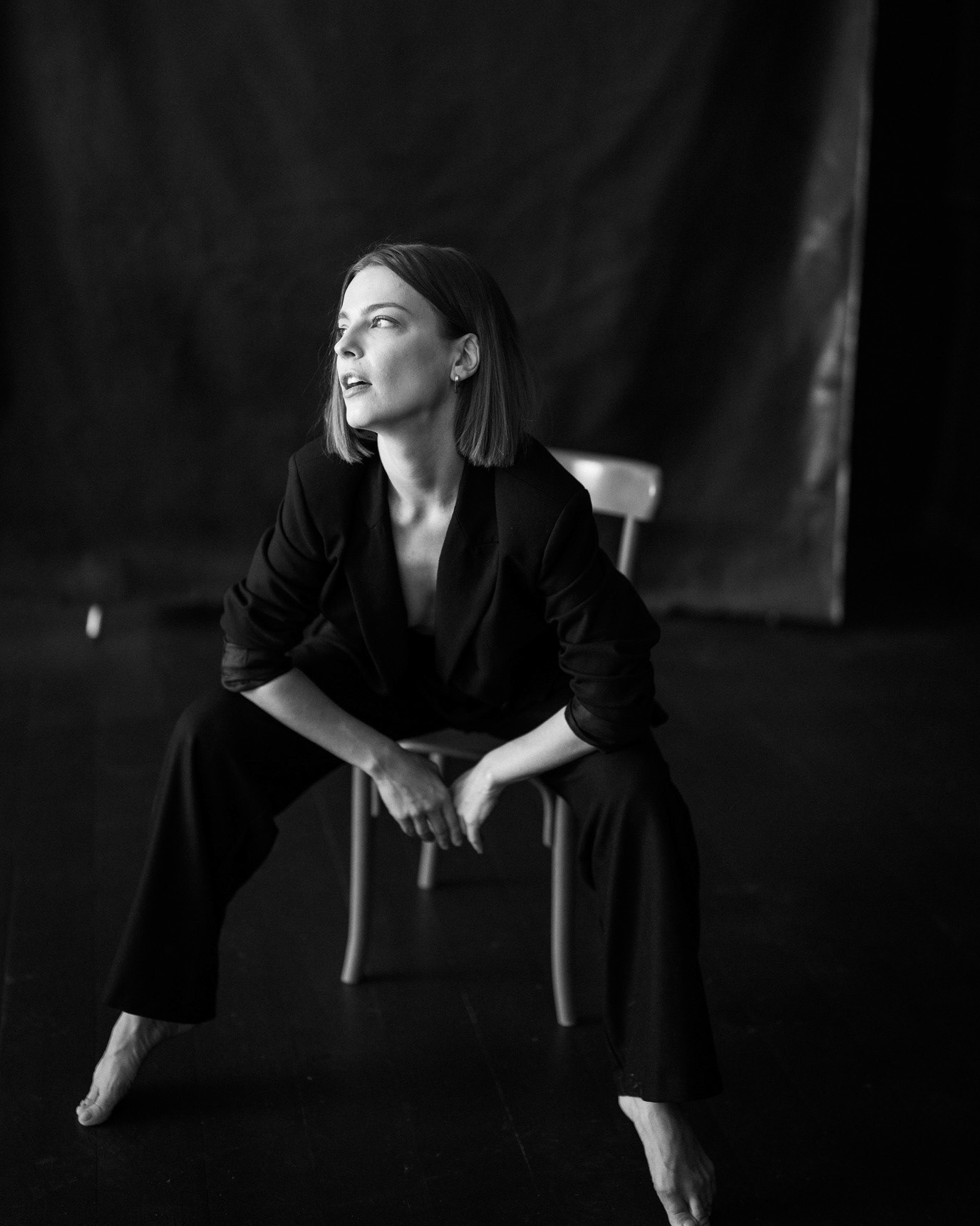 Black-and-white portrait of model Iuliana Nae seated in a dark suit and laughing, photographed by Alex Gâlmeanu.