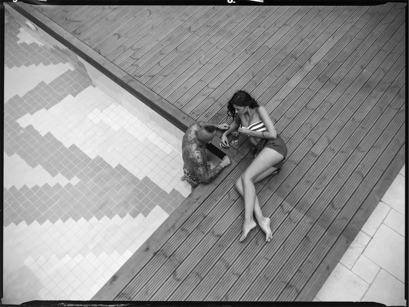 Alex Velea and Antonia relaxing beside a swimming pool in an overhead black-and-white portrait, photographed by Alex Gâlmeanu.