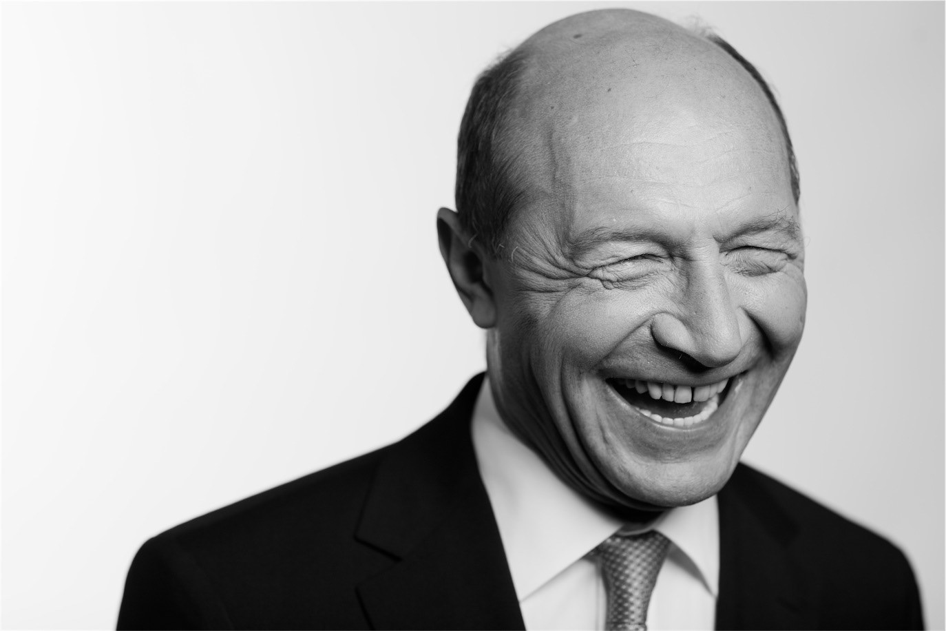Black-and-white portrait of Traian Băsescu laughing with his eyes closed, photographed by Alex Gâlmeanu.