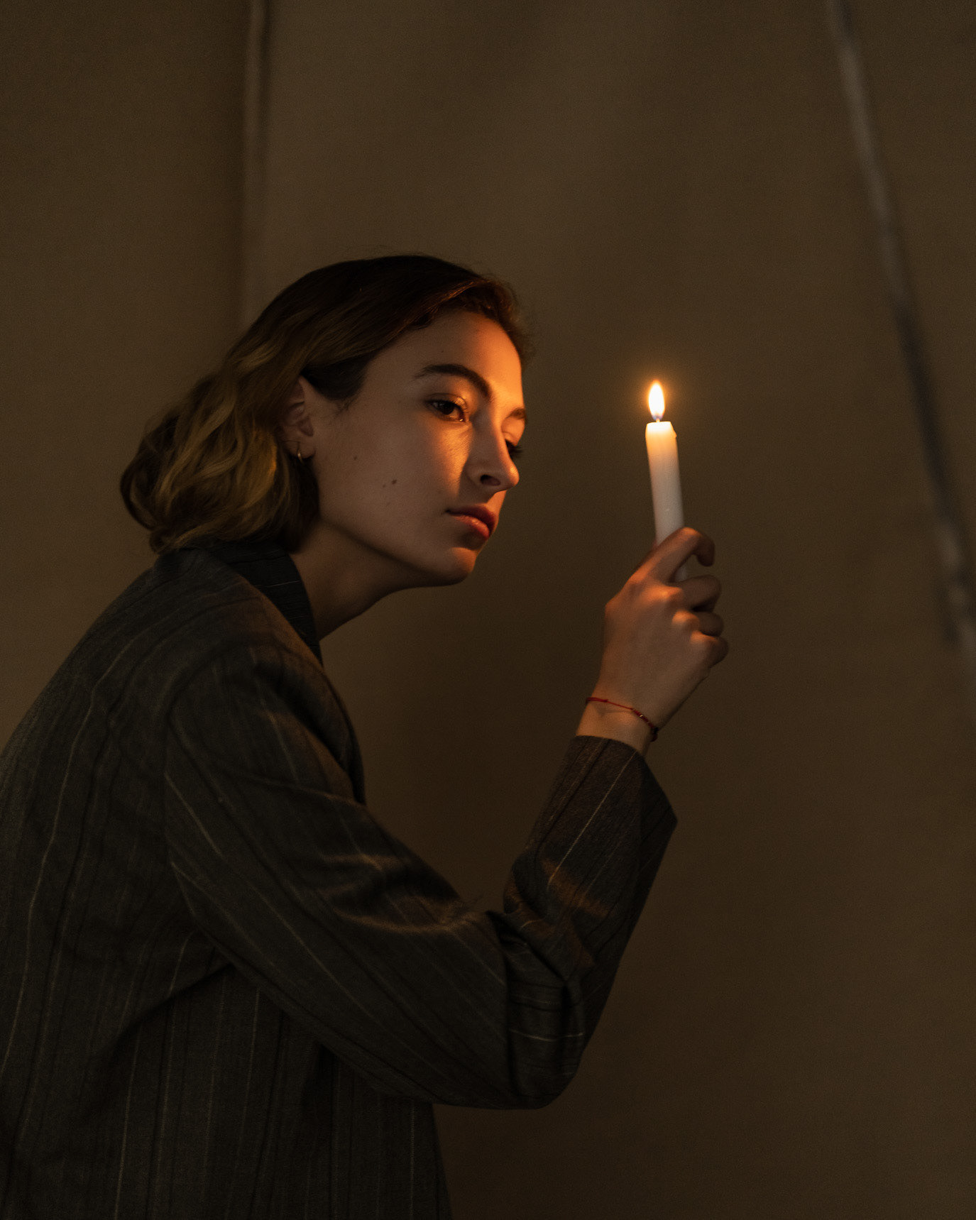 Portrait of actor Irina Artenii holding a lit candle in a dark studio, photographed by Alex Gâlmeanu.