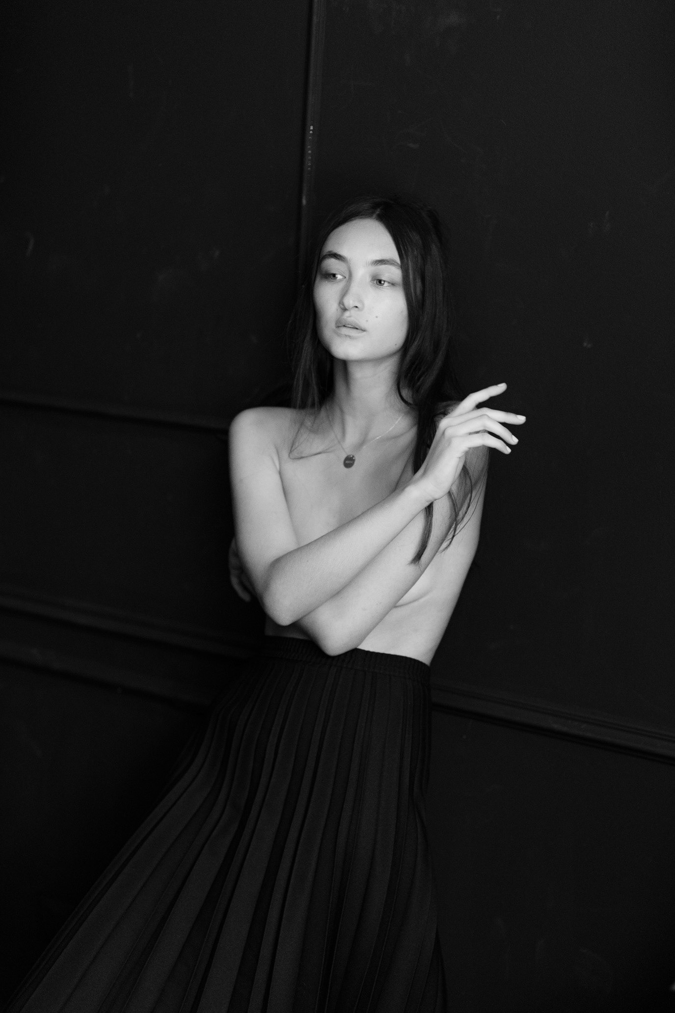 Black-and-white portrait of model Anisa Mustafa seated with bare shoulders against a dark background, photographed by Alex Gâlmeanu.