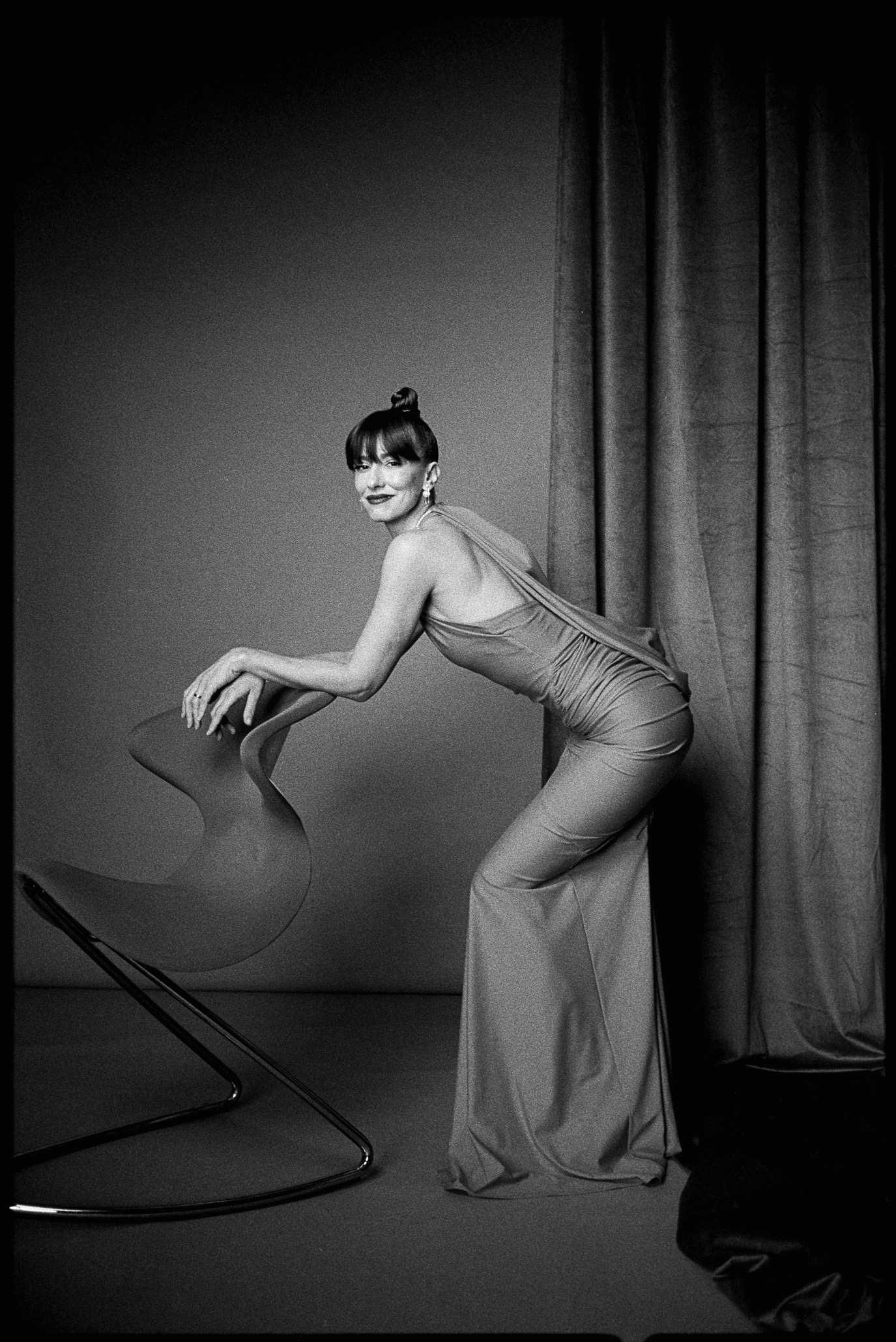 Dana Rogoz posing beside a sculptural chair in an elegant black-and-white portrait, photographed by Alex Gâlmeanu.