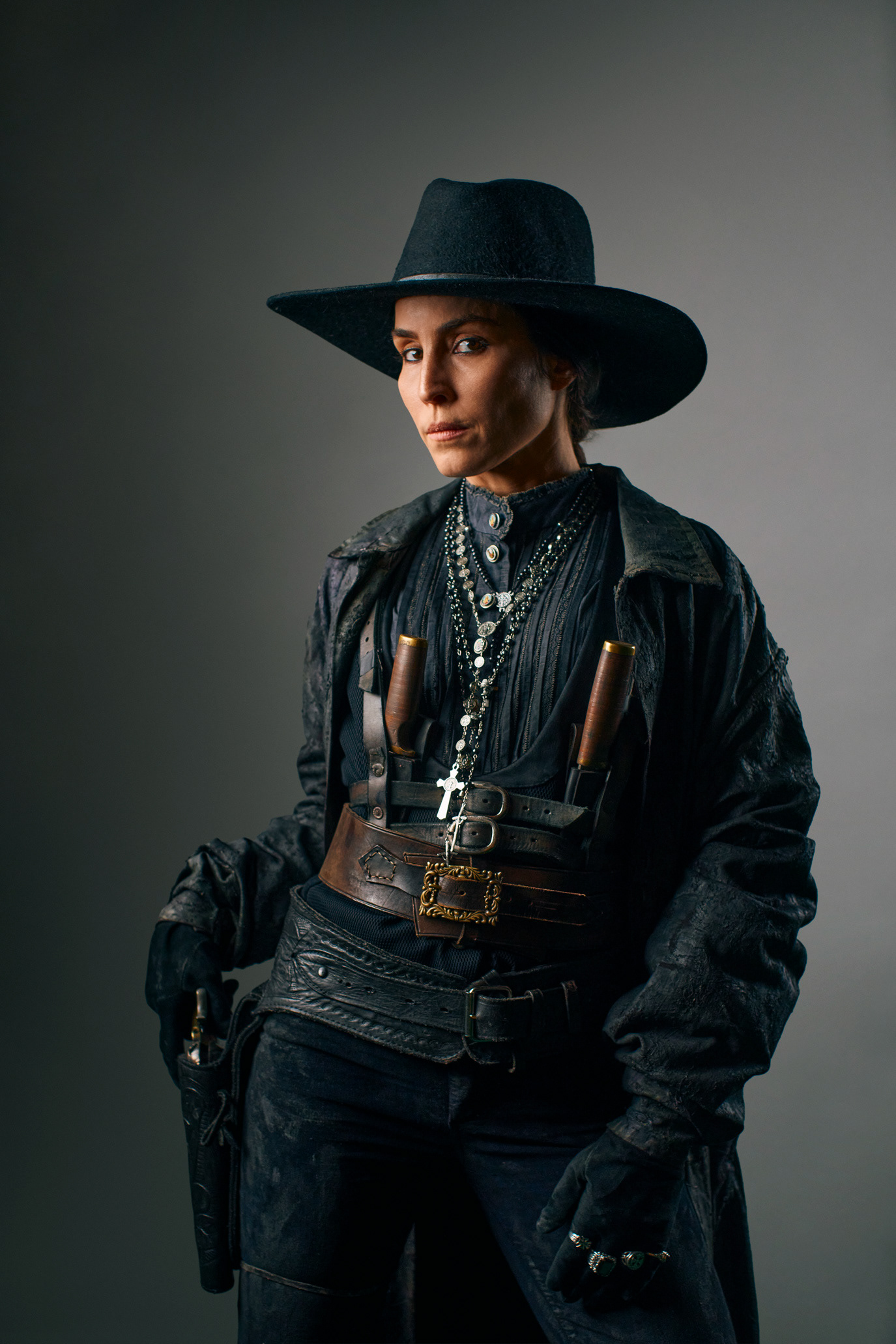 Noomi Rapace in a dark western costume with a wide-brimmed hat and holsters, photographed by Alex Gâlmeanu.