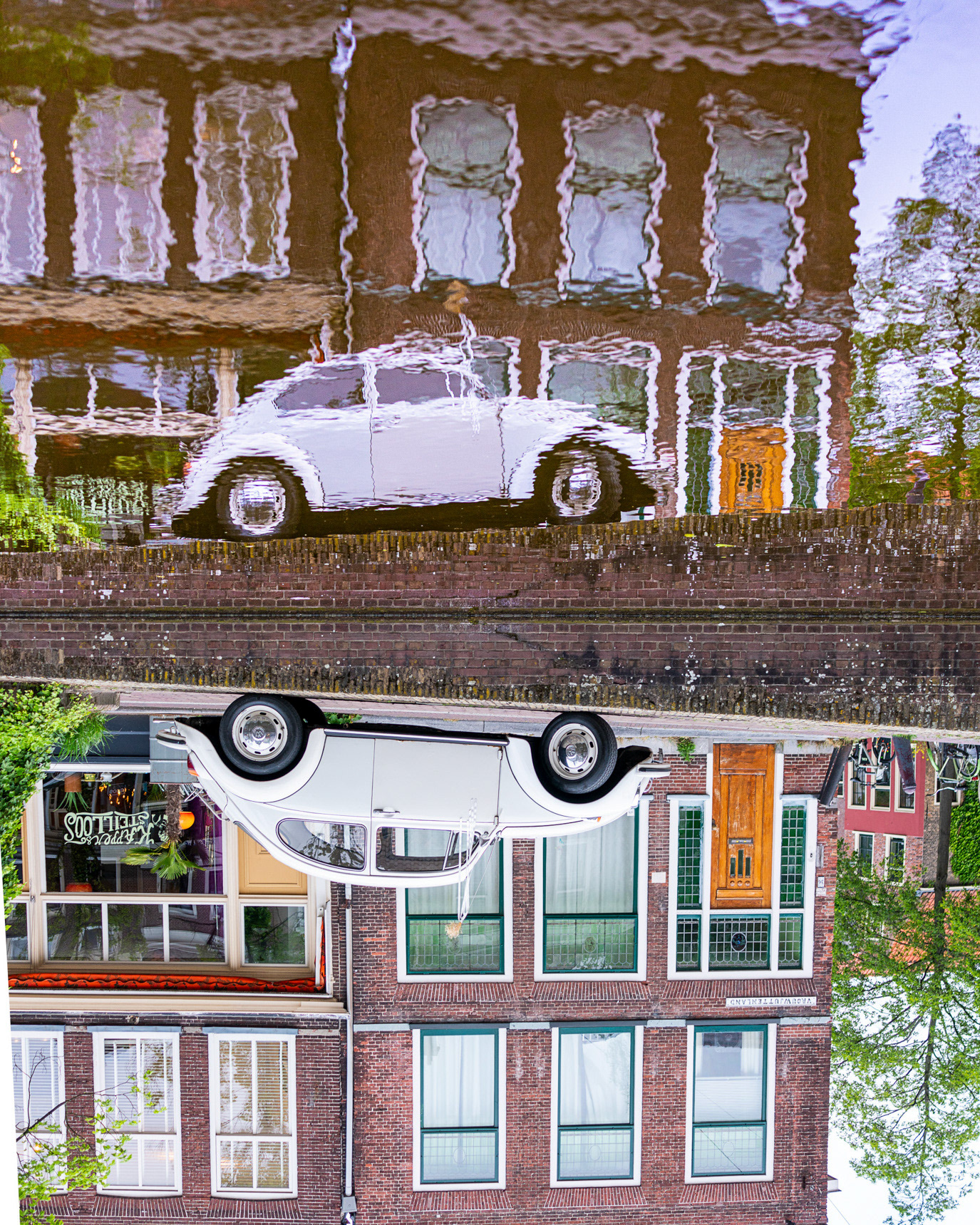 A canal reflection and a white car forming an inverted cityscape in Utrecht, Netherlands. Photograph by Alex Galmeanu.