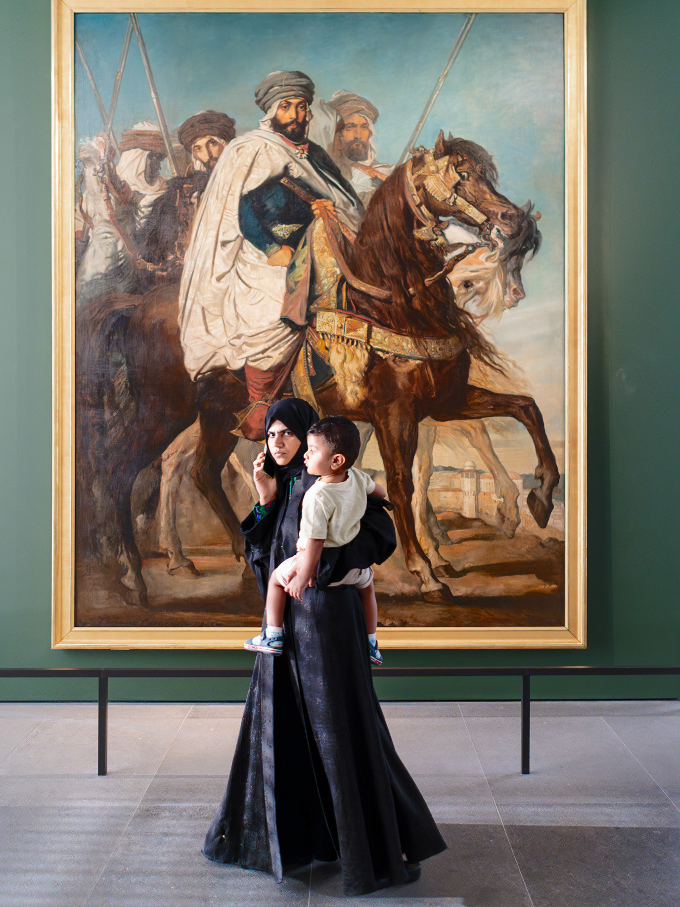 A women with her child posing beneath a monumental equestrian painting in Abu Dhabi, UAE. Photograph by Alex Galmeanu.