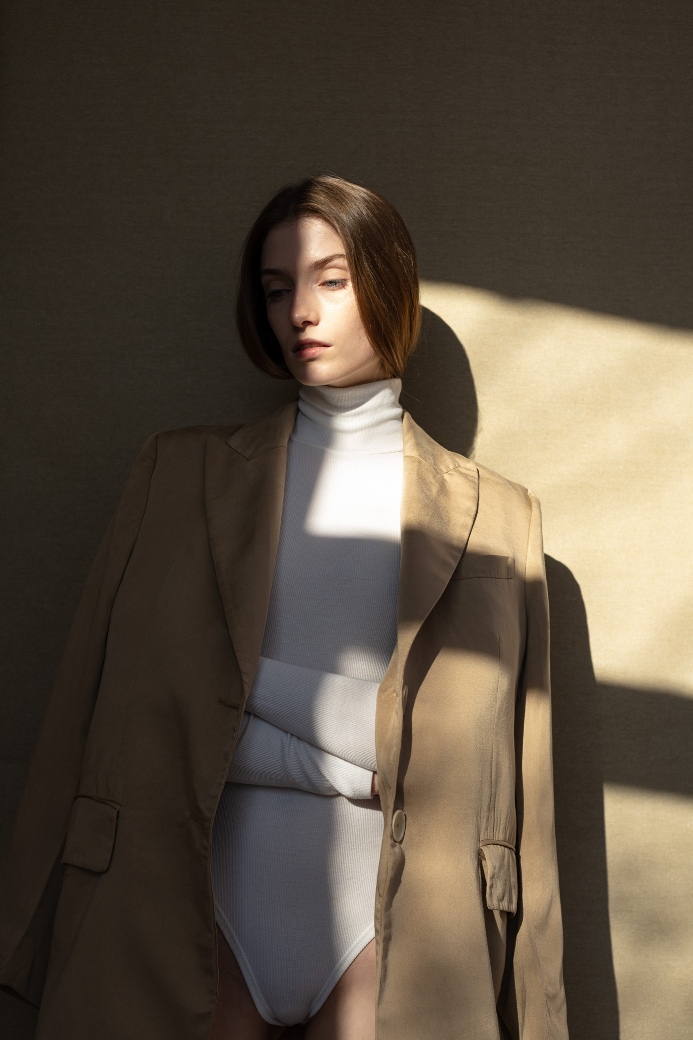 Portrait of model Beatrice Coriciuc in a beige jacket crossed by geometric sunlight, photographed by Alex Gâlmeanu.