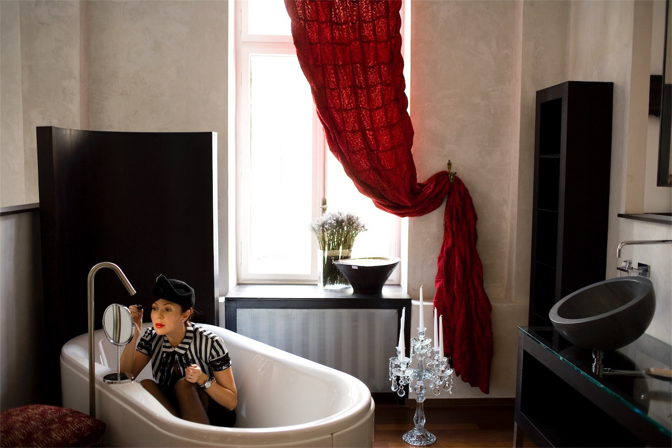 Venera Arapu seated in a bathtub beneath a flowing red curtain, photographed by Alex Gâlmeanu.