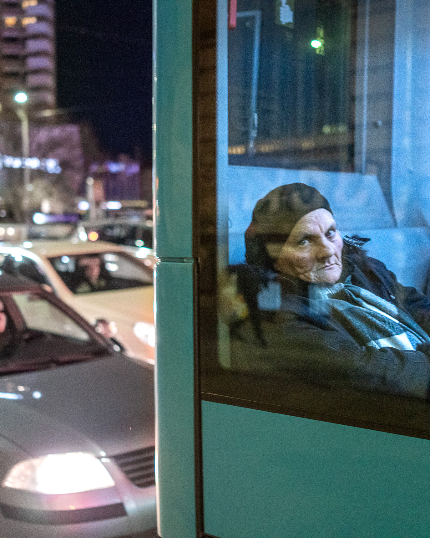 A passenger seen through layered bus and traffic reflections in Bucharest, Romania. Photograph by Alex Galmeanu.