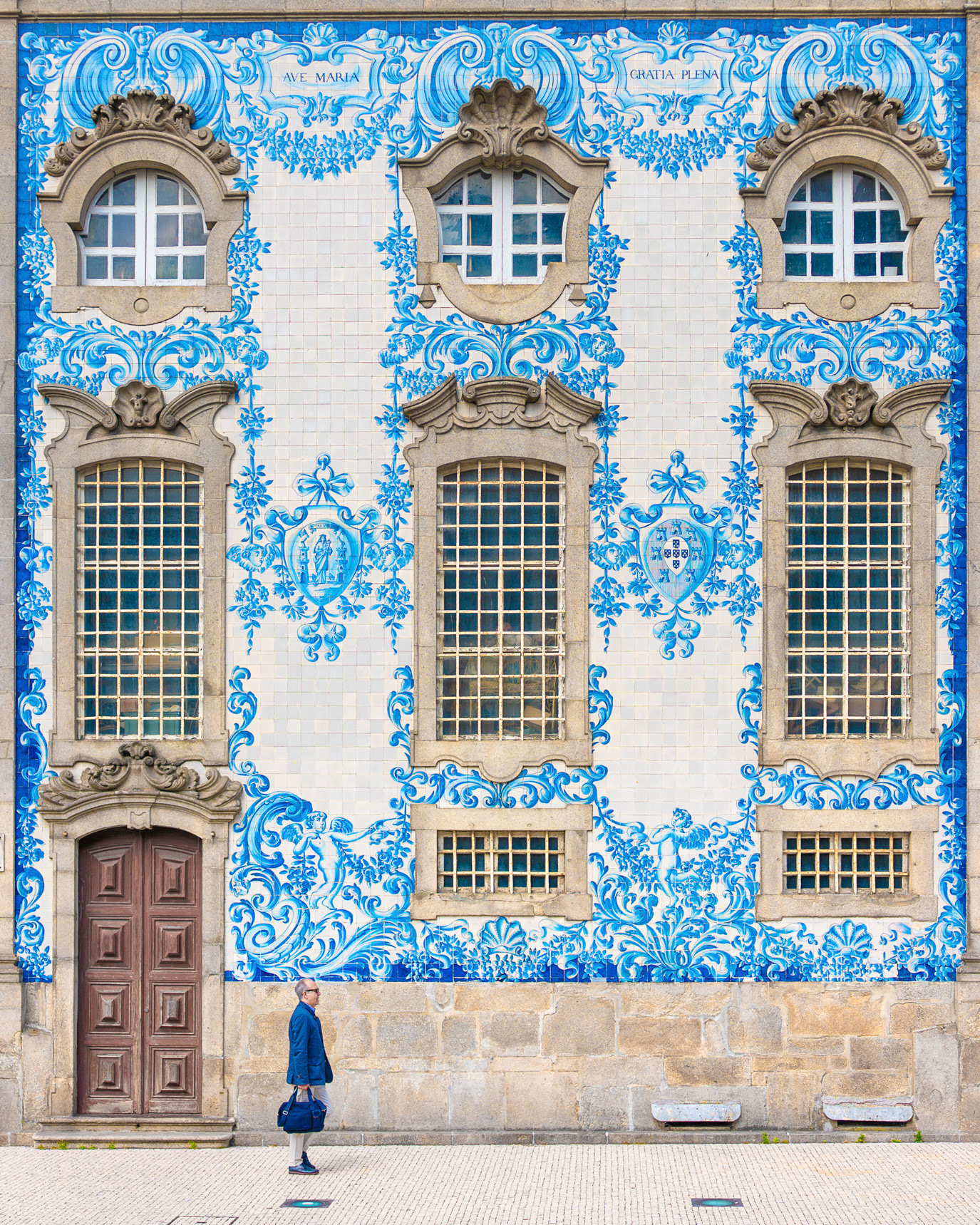 A solitary man before an ornate blue-tiled facade in Porto, Portugal. Photograph by Alex Galmeanu.