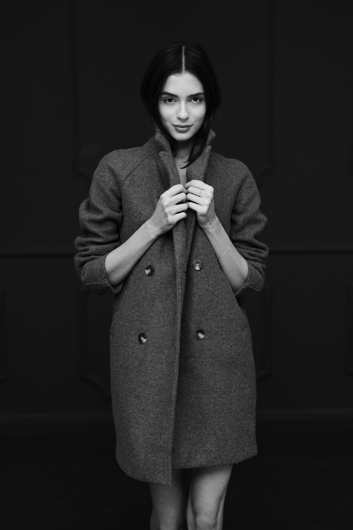 Black-and-white portrait of model Madalina Nicolae holding the collar of an oversized coat, photographed by Alex Gâlmeanu.