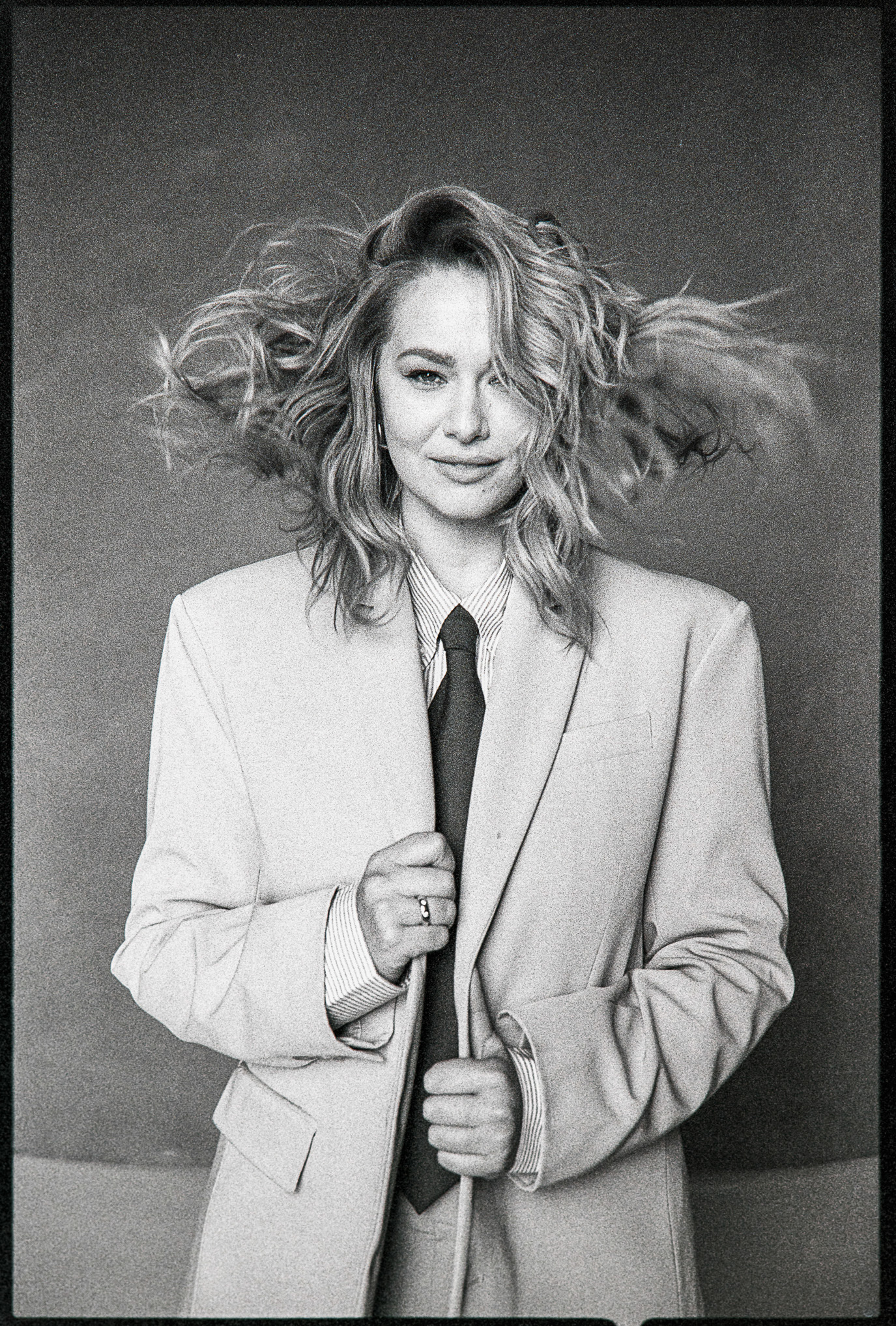 Feli in an oversized suit and tie with her hair in motion, photographed in black and white by Alex Gâlmeanu.
