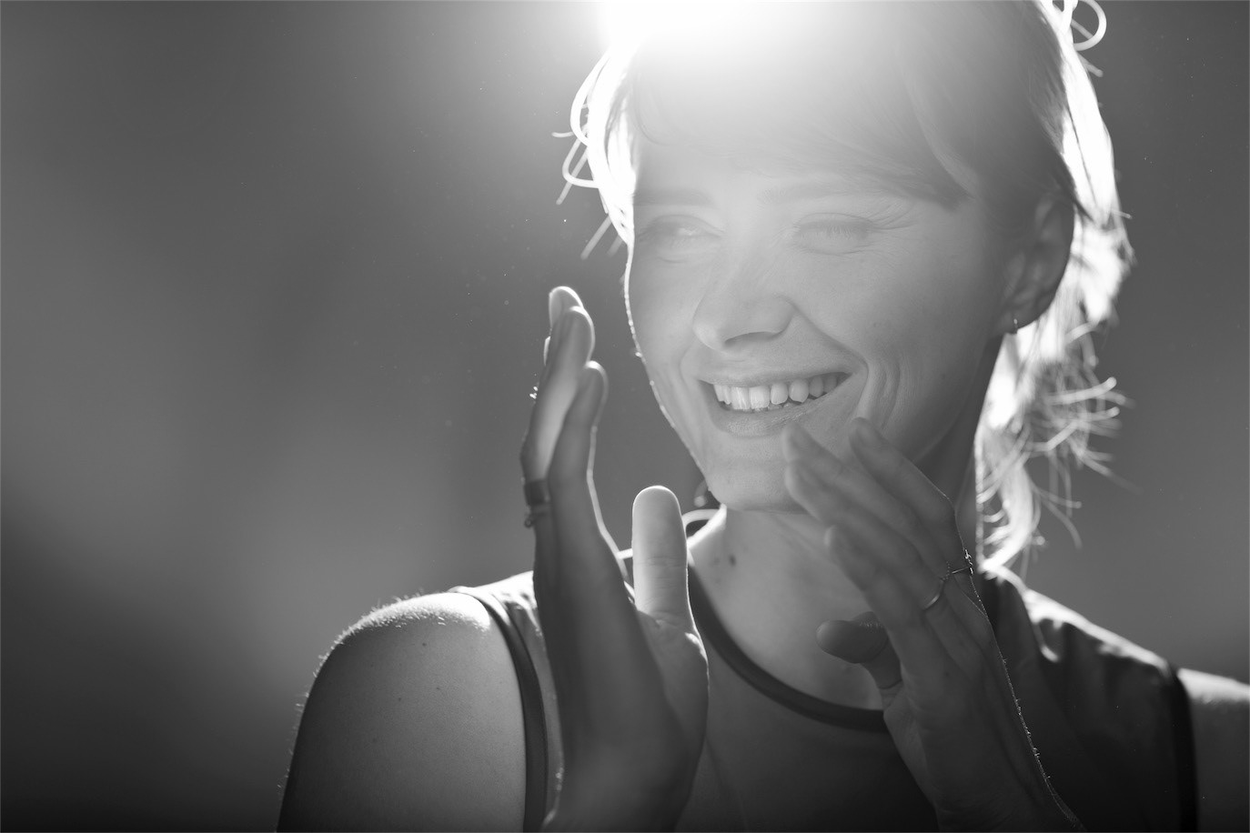 Backlit black-and-white portrait of Maria Popistașu smiling with her hands raised, photographed by Alex Gâlmeanu.